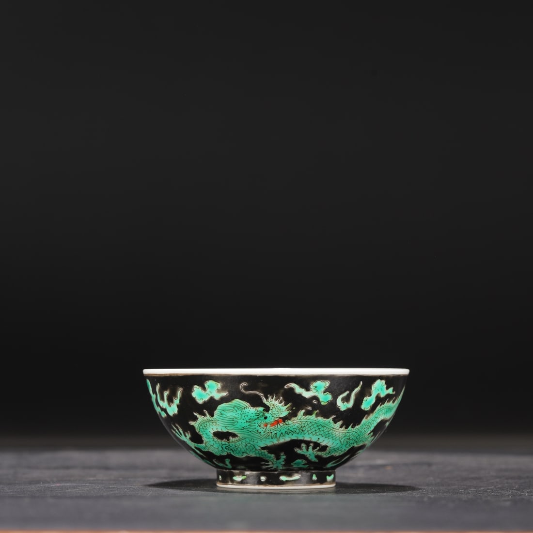 A Qing Dynasty Kangxi period black-ground green-enamel dragon and cloud design tea bowl, formerly in: Dimensions: Height 4.3 cm, Diameter 9.8 cm.