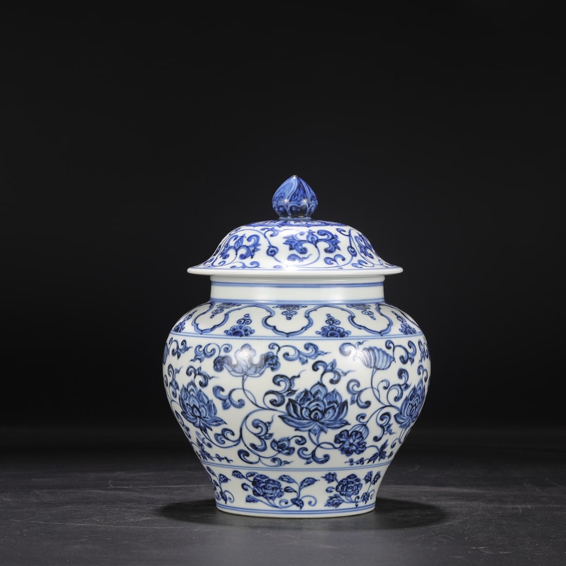 A large covered blue-and-white porcelain jar with a scrolling floral design from the Yongle period: Dimensions: Height 27.5 cm, Mouth diameter 14.5 cm, Belly diameter 20 cm.