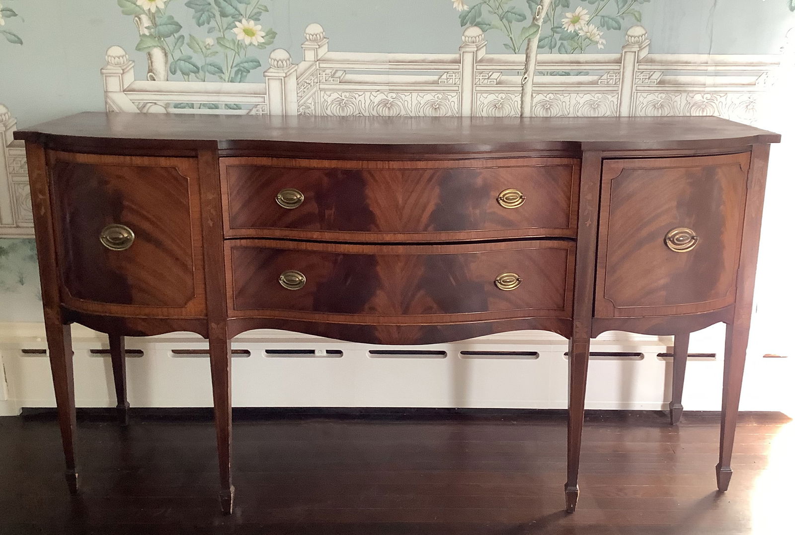 Mahogany Hepplewhite-Style Sideboard: The sideboard has a serpentine front and brass hardware. Features swirly crotch mahogany verniers and inlaid details. 70x22.5x37.5