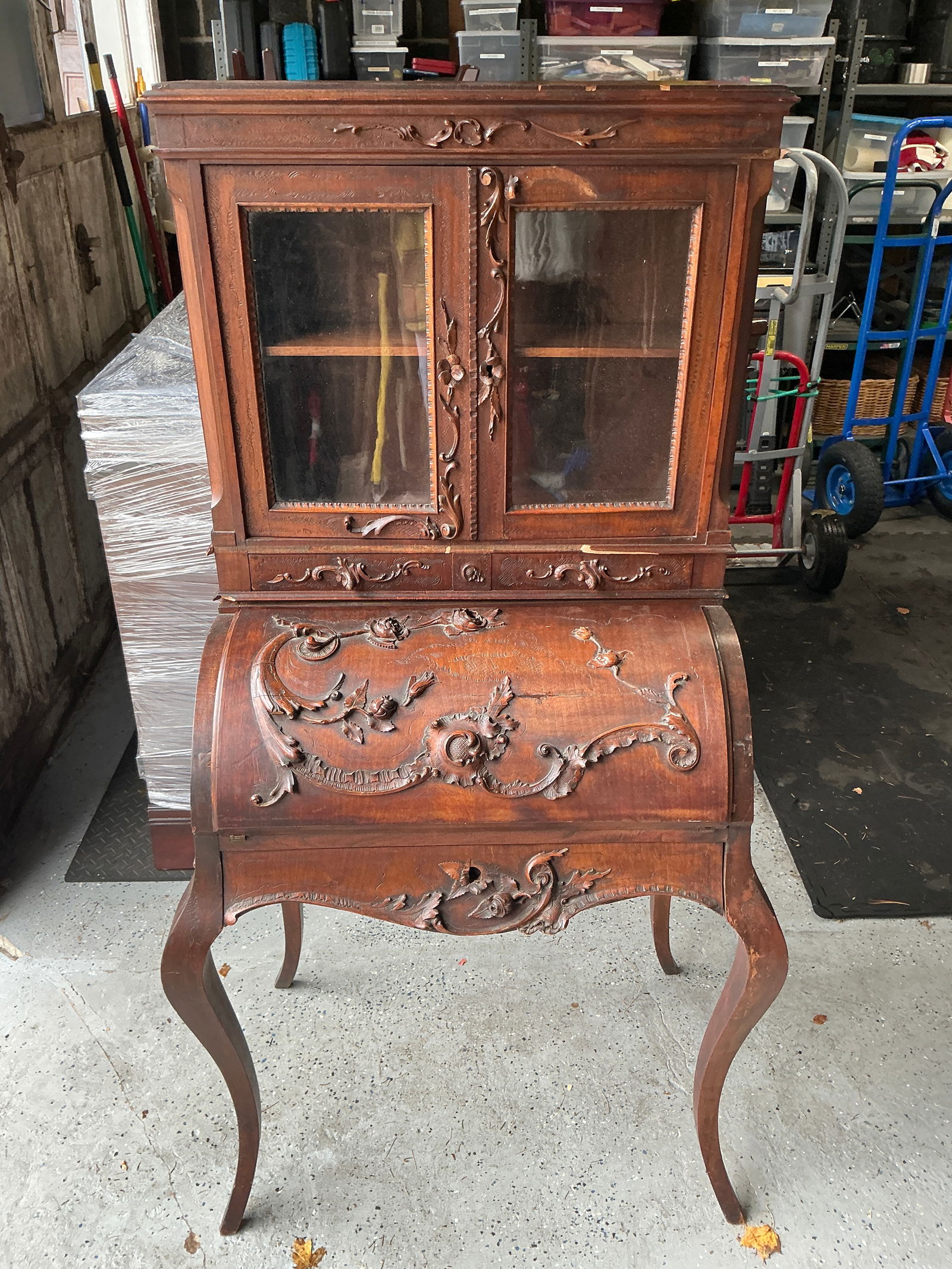 Antique French Louis XV-style carved wood secretary desk: Antique French Louis XV-style carved wood secretary desk that combines vertical storage with a roll-top or drop-front writing surface. The piece features extensive, detailed Rococo-style carvings on t