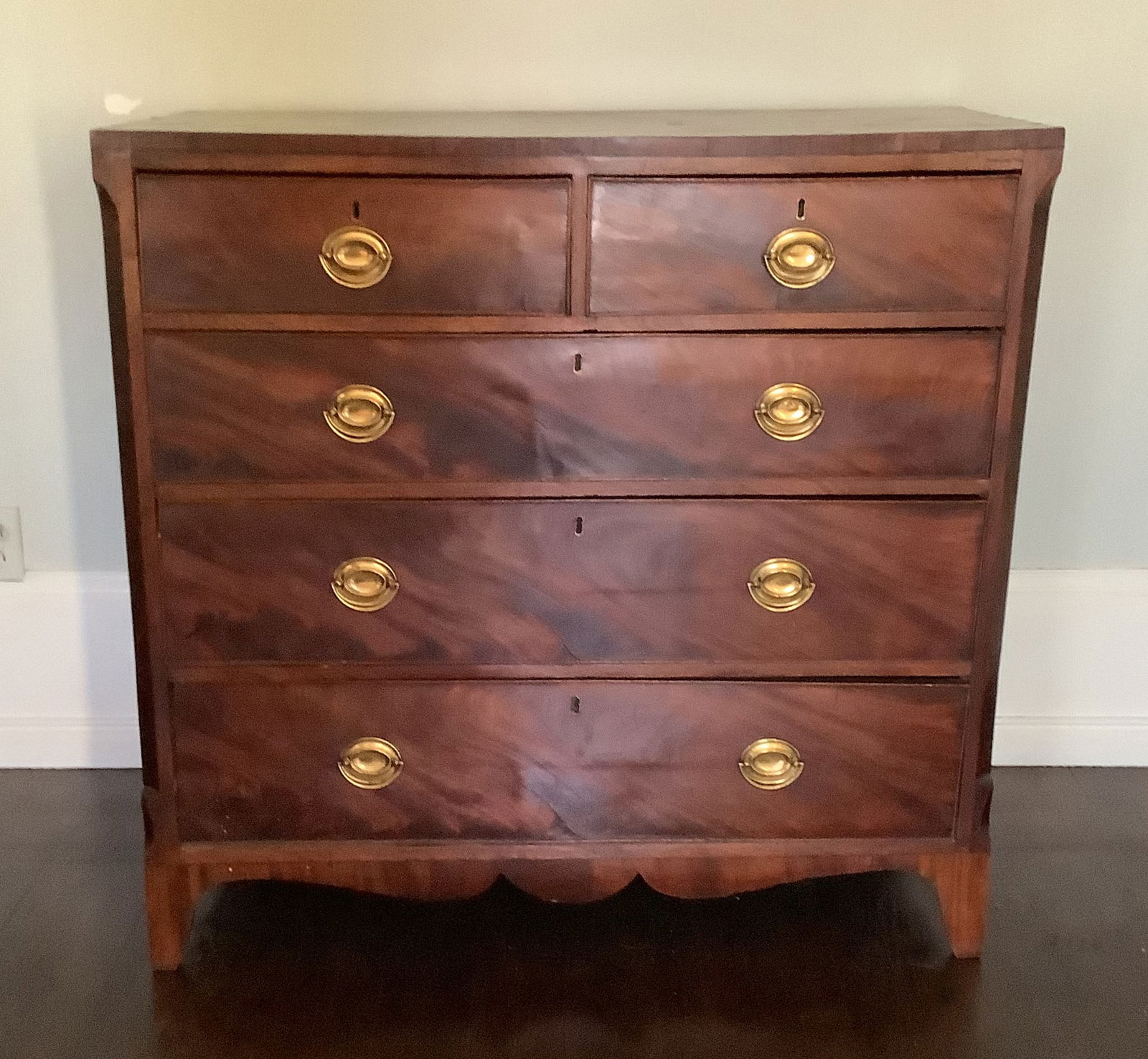 Mahogany Chest of Drawers: Dated to the early 19th century, this chest features four graduated drawers with oval brass pulls and shaped bracket feet. An authentic piece of early American craftsmanship41.5x19.5x39