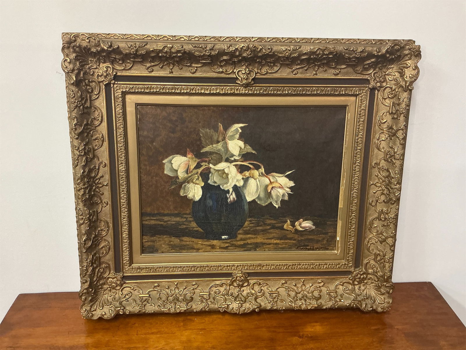 Antique Oil on Canvas: This exquisite antique oil on canvas features a beautiful still life composition. The artwork showcases a striking arrangement of pale flowers elegantly set in a deep blue vase, resting on a textured