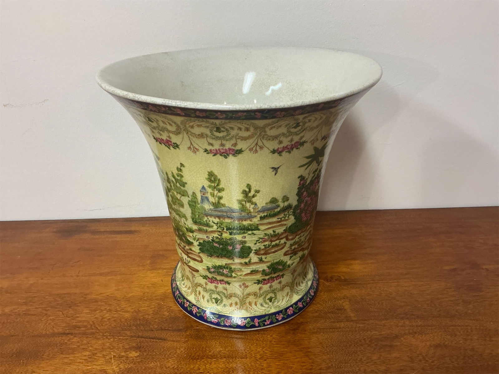 Antique Porcelain Vase: This antique porcelain vase features an exquisite design with vibrant hand-painted scenes of lush gardens and serene landscapes. The decorative details include floral motifs and intricate borders,
