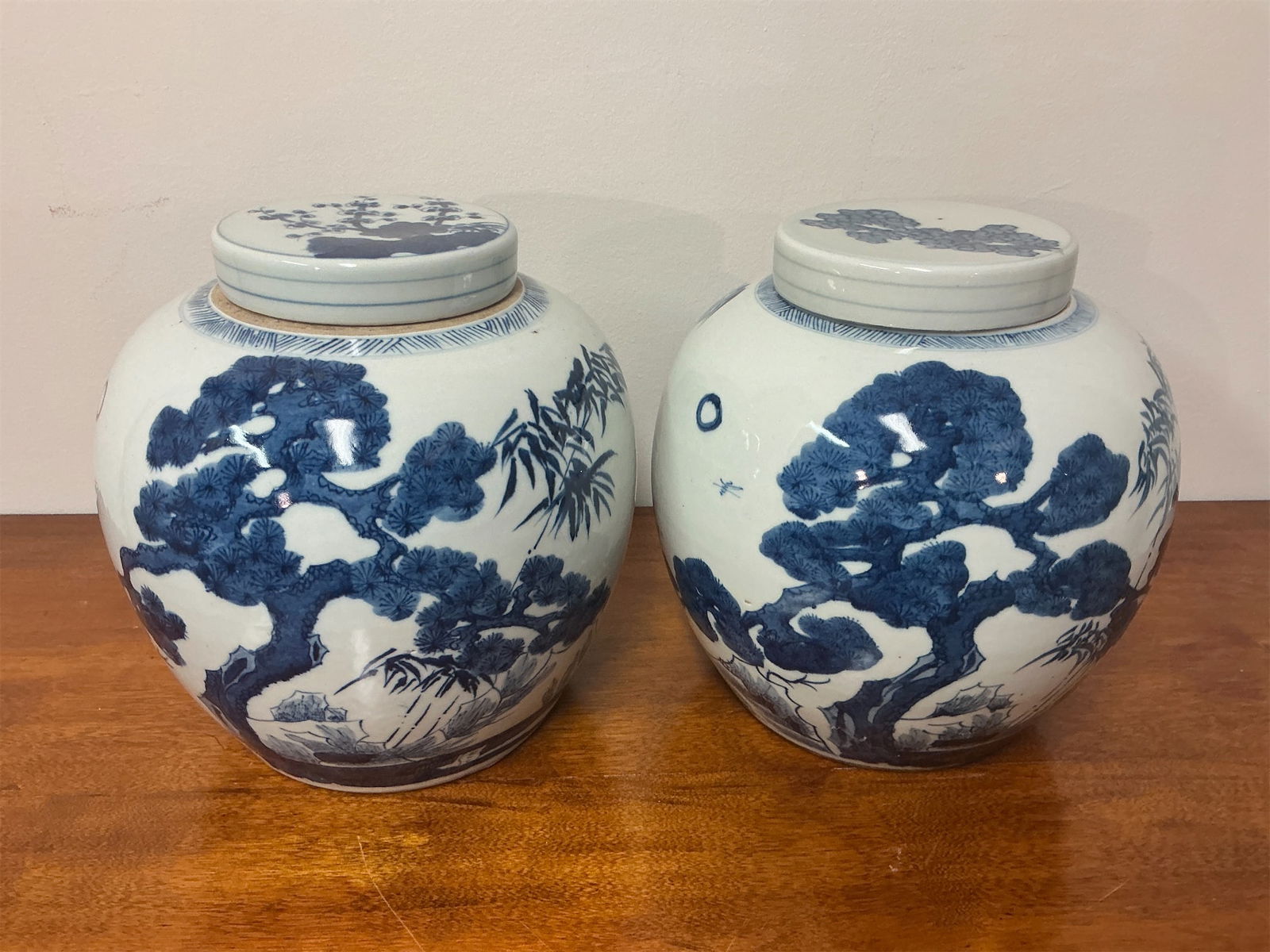Antique Lidded Porcelain Ginger Jars: This pair of antique lidded porcelain ginger jars showcases exquisite craftsmanship with intricate blue and white designs. Each jar features stunning depictions of natural scenes including trees,