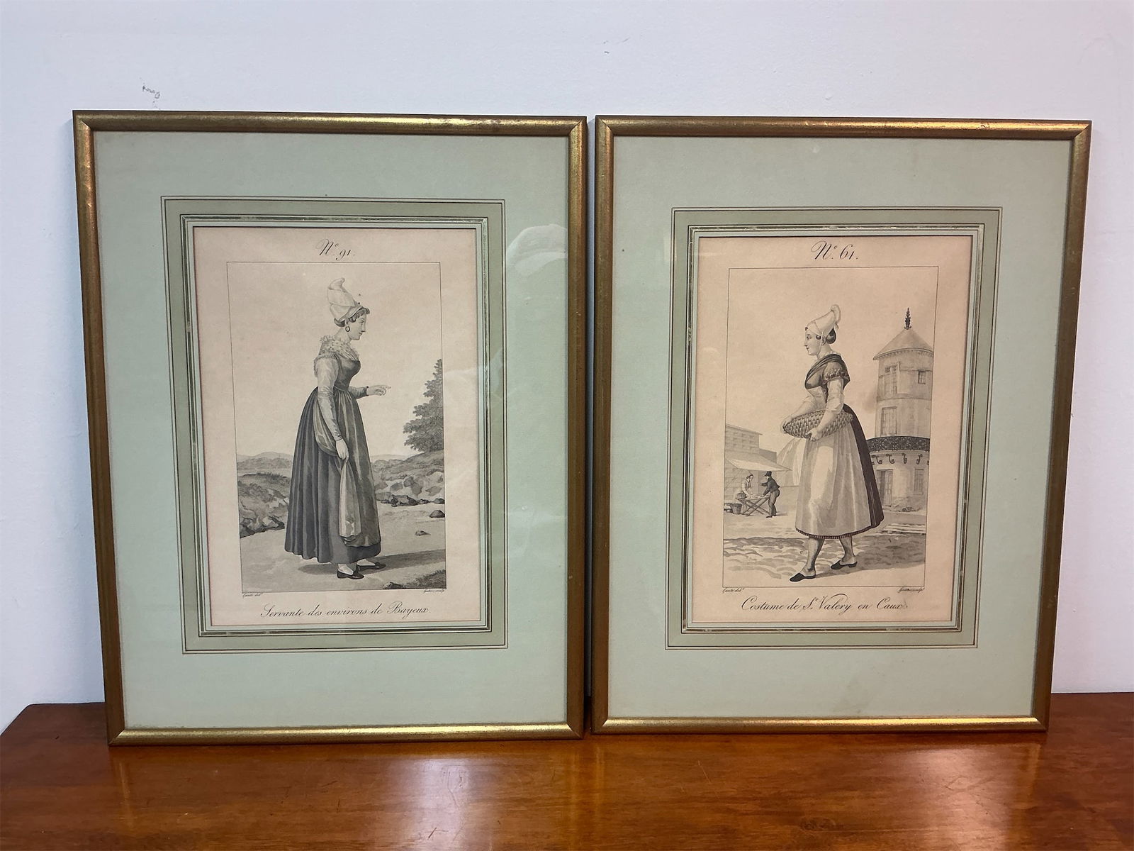 Vintage Framed Prints of Hand-colored engravings of SS Normandie Lunch Menu: Pair of vintage framed prints depicting traditional costumes. Each print showcases elegant figures in detailed attire, capturing the essence of historical fashion. The first print, labeled "Servante