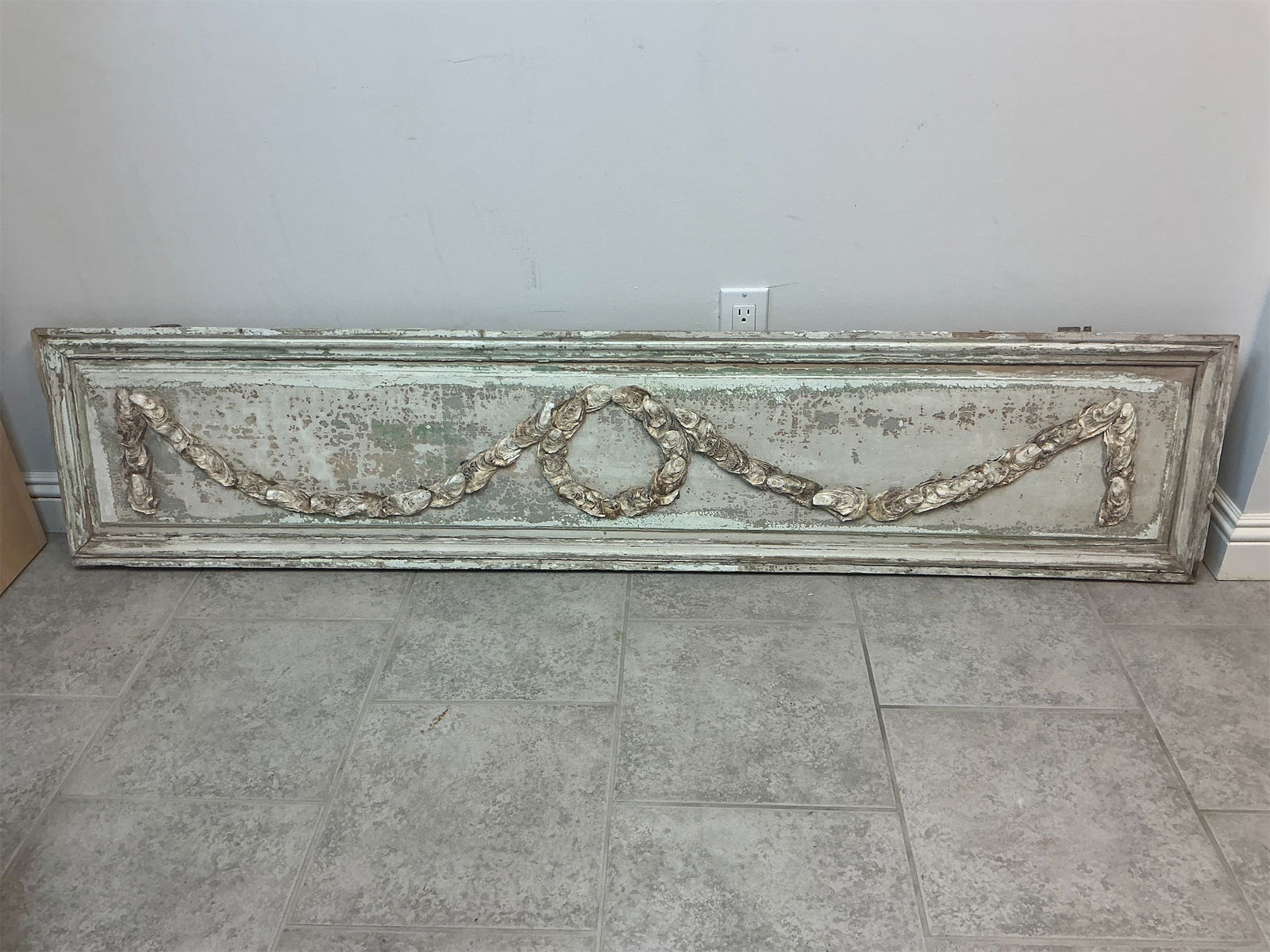 Wooden wall hanging: This wooden wall hanging showcases a unique design featuring oyster shells and a weathered finish that adds character to any space. The centerpiece is an intricate pattern that resembles intertwined