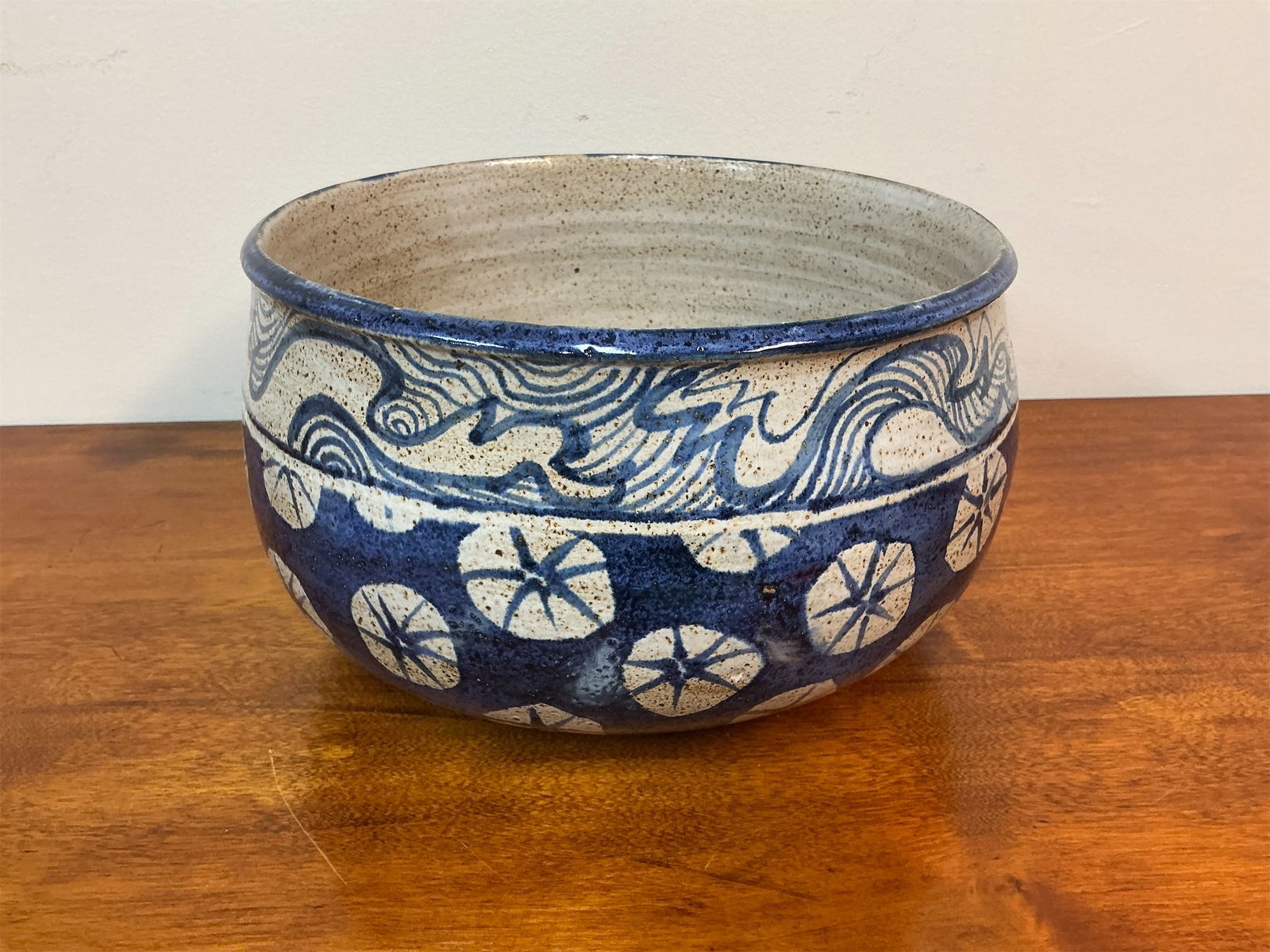 Signed Studio Pottery Hand-painted Glazed Bowl and 5 Cups: This striking hand-painted glazed bowl and five cups showcase intricate designs in a rich blue and natural tone, perfect for both decorative and functional use. The exterior features a dynamic wave