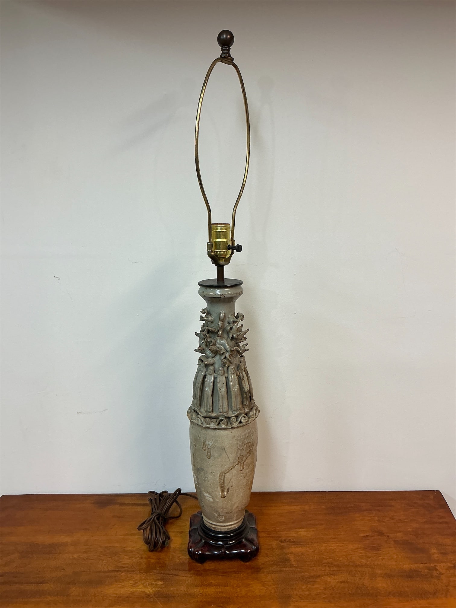 Chinese Celadon Qingbai Urn later mounted as lamp: This unique piece is a Chinese Celadon Glazed Qingbai Funeral Urn, later repurposed as a lamp. The urn features intricate detailing, with a beautifully sculpted neck adorned with figures and floral