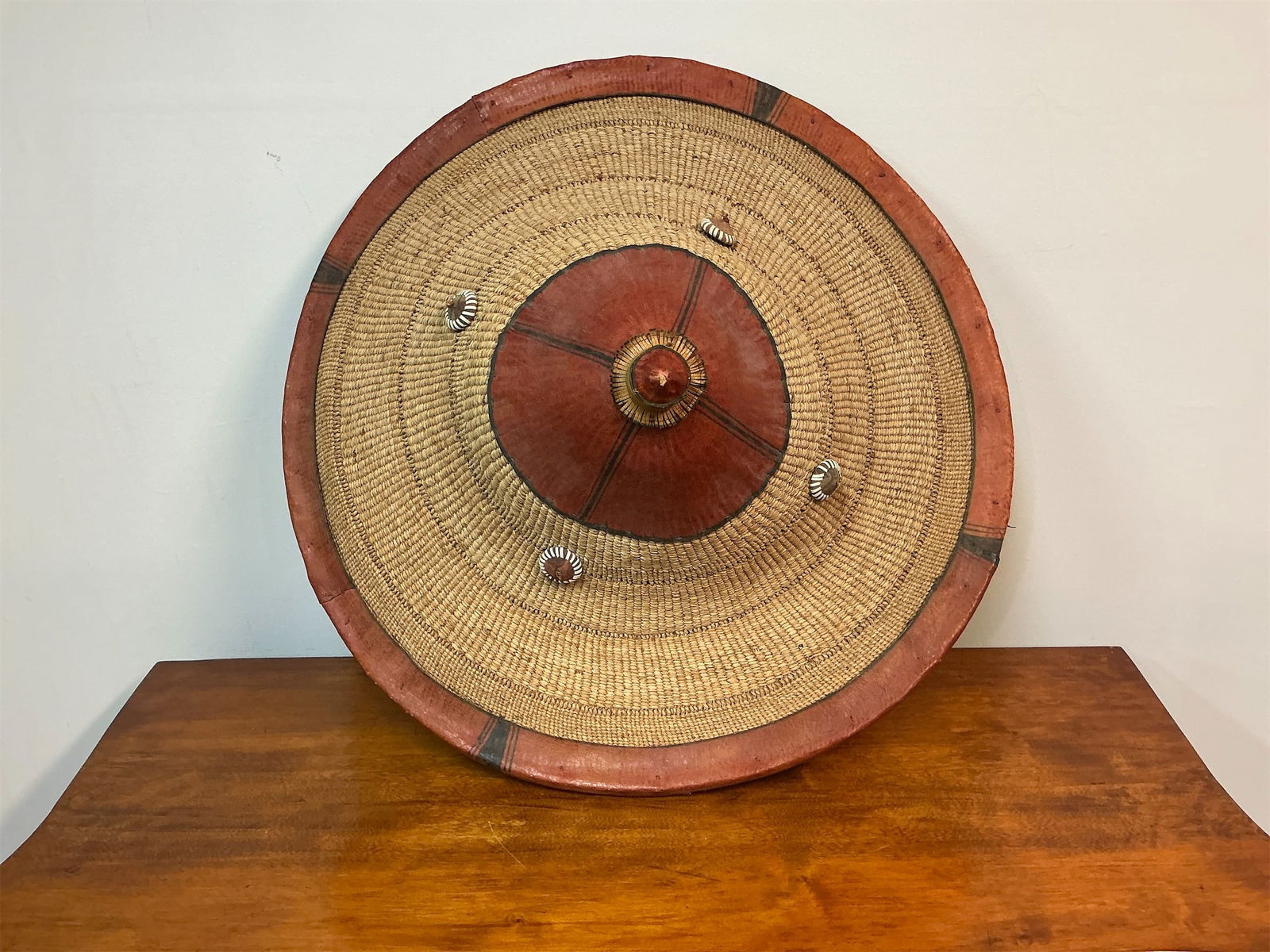 Vintage African Fulani Tribal Hat: African Fulani tribal hat showcases intricate craftsmanship and cultural significance. The hat features a wide, circular design made from woven materials, accented with vibrant red and black