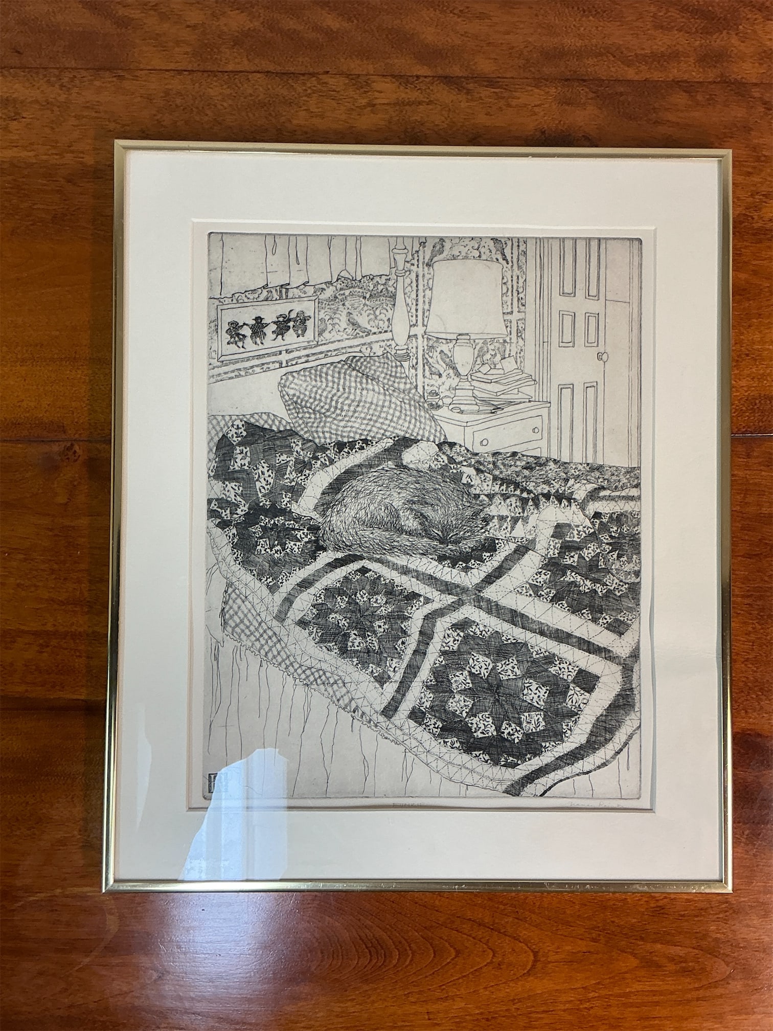 Black & White engraving Funkie signed and numbered: Striking black and white engraving titled "Funkie" captures a serene scene featuring a curled-up animal resting on a beautifully patterned quilt. The intricate details of the quilt and the
