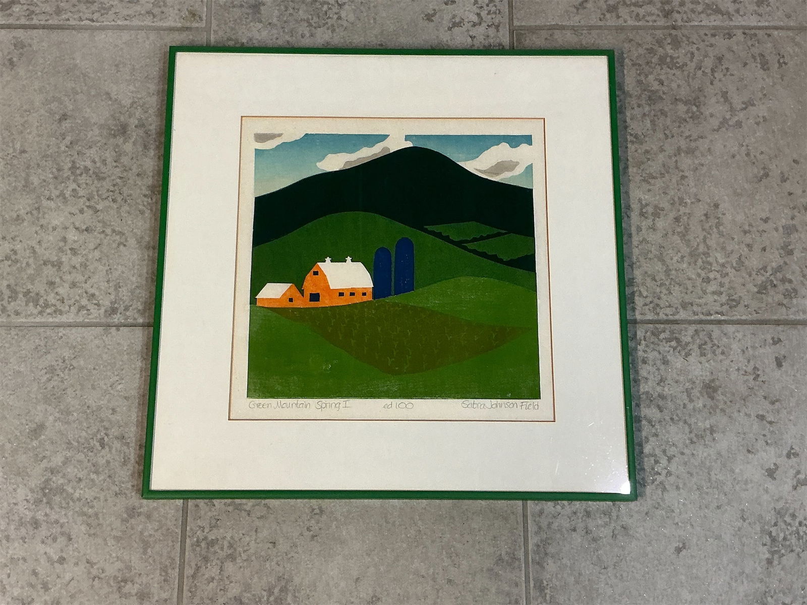 Framed silk screen Green Mountain Spring I by Sabra Johnson Field ed100: Framed silk screen titled Green Mountain Spring I by artist Sabra Johnson Field, numbered edition 100. This piece features a vibrant landscape showcasing rolling green hills, a classic red barn,