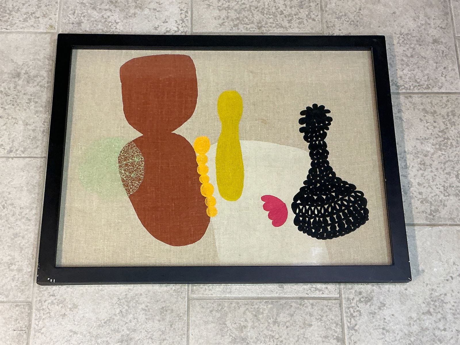 Framed Yellow Spoon Stich Art: Mid-century framed yellow spoon stitch art showcases a vibrant and abstract design featuring playful shapes and colors. The artwork prominently displays a combination of earthy tones, including rich b