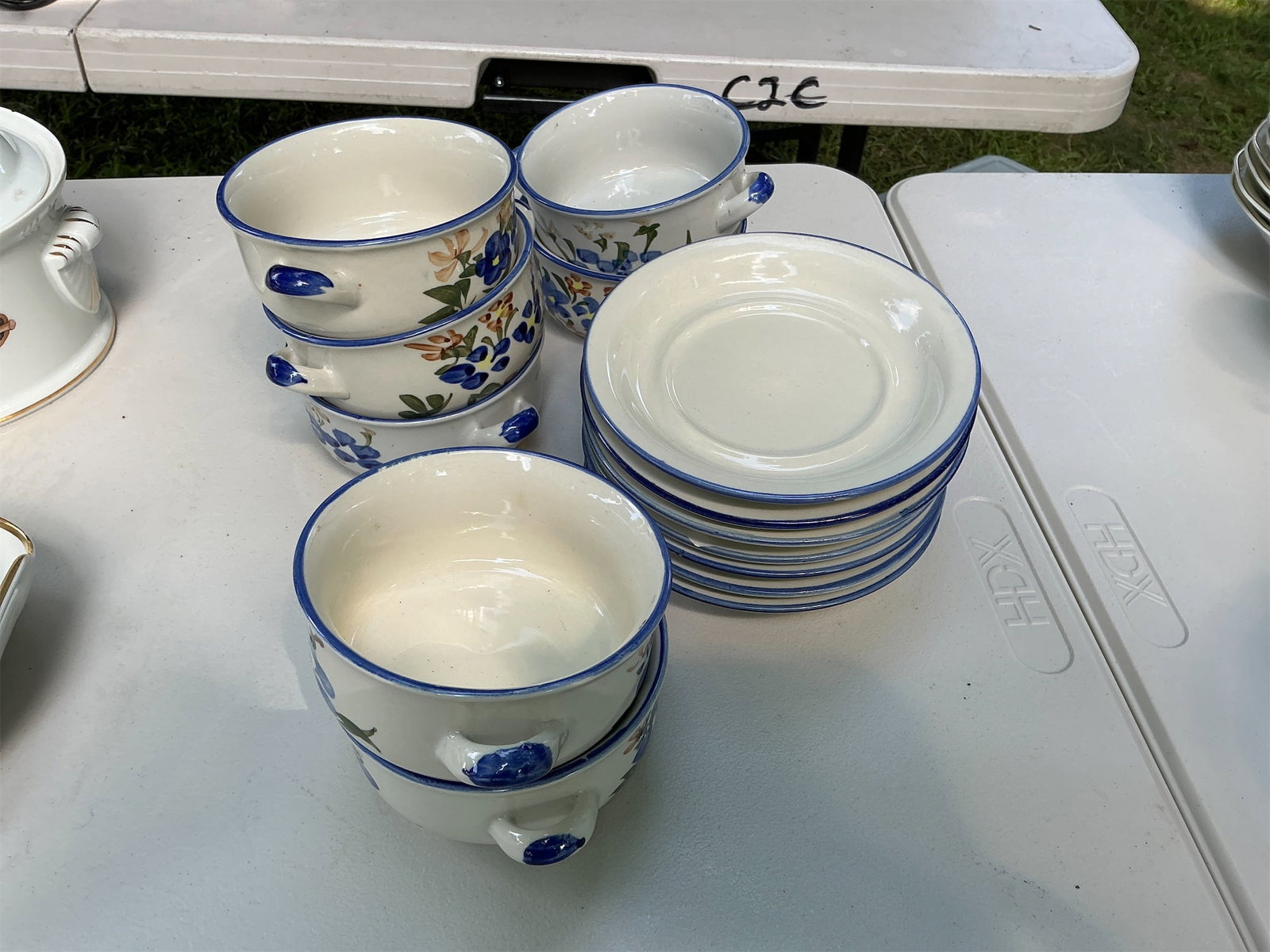Chi Jiang Soup Bowls and Saucers: Set of Chi Jiang Soup Bowls and Saucers featuring a charming floral design with blue accents. This collection includes multiple soup bowls, each equipped with dual handles for easy serving,