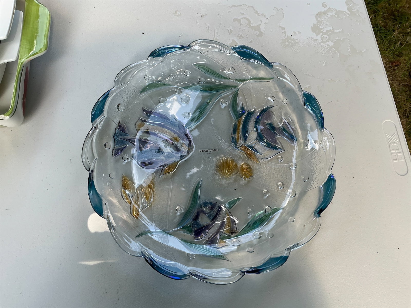Savoir Vivre Decorative Plate: This Savoir Vivre Decorative Plate features a stunning design with intricate detailing of fish and seashells, all set against a clear, textured background. The plate has a scalloped edge, accented
