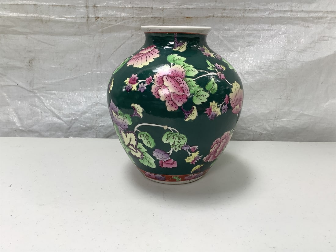 April Cornell Floral Vase: This April Cornell Floral Vase showcases an exquisite design featuring vibrant floral patterns against a rich green background. The elegant shape, with a gently rounded body tapering to a narrow