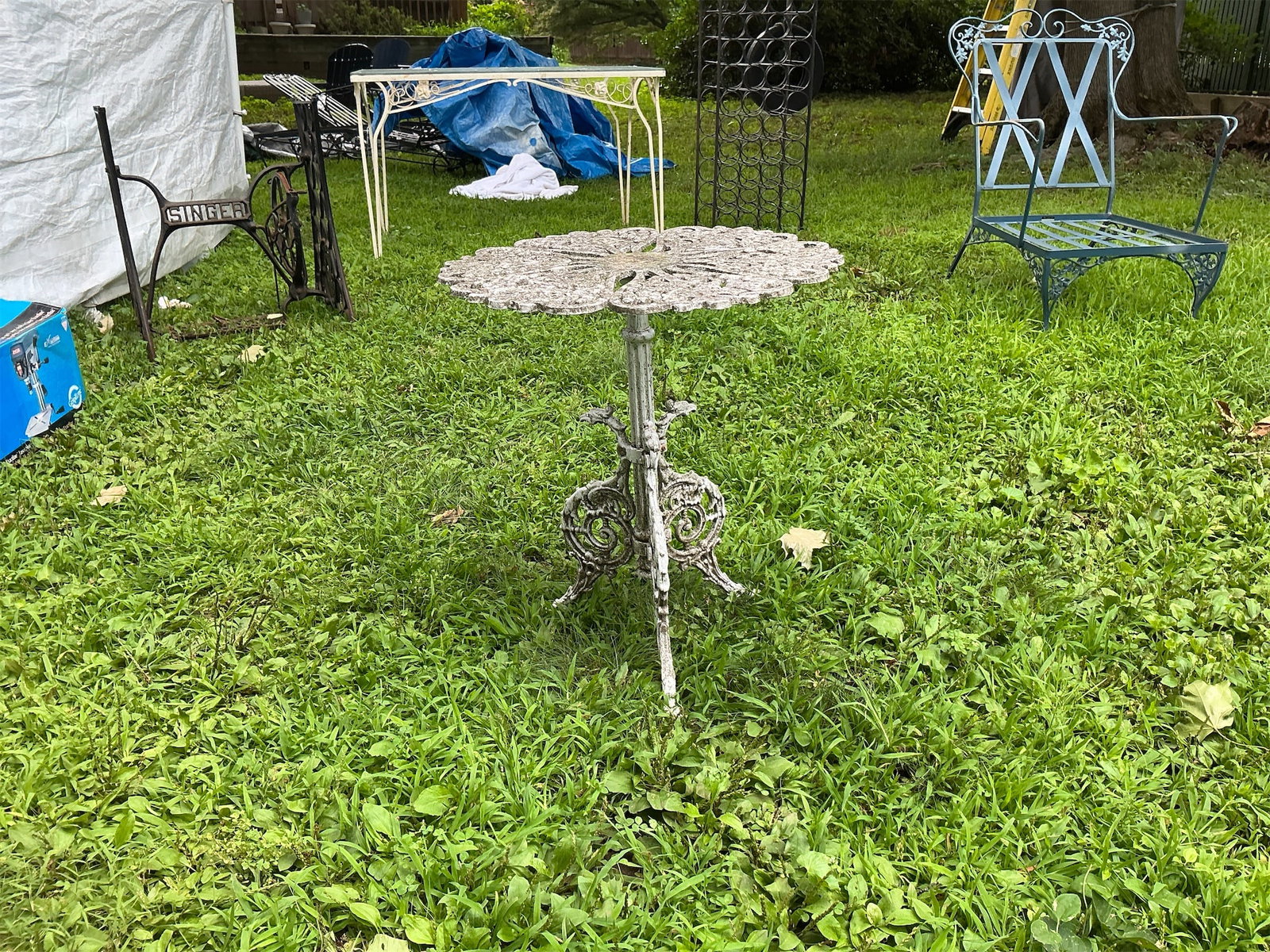 Ornate Iron Outside Sidetable: This ornate outside sidetable showcases a beautifully designed floral pattern on its round tabletop, perfect for adding a touch of elegance to any outdoor space. The intricate details and