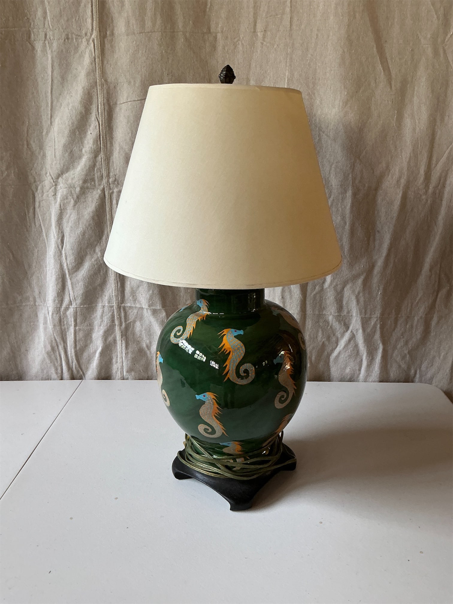 Green Seahorse Lamp: Add a touch of nautical charm to your home with this Green Seahorse Lamp. The vibrant green ceramic base features beautifully detailed seahorse motifs in blue and orange, adding a whimsical flair. Com