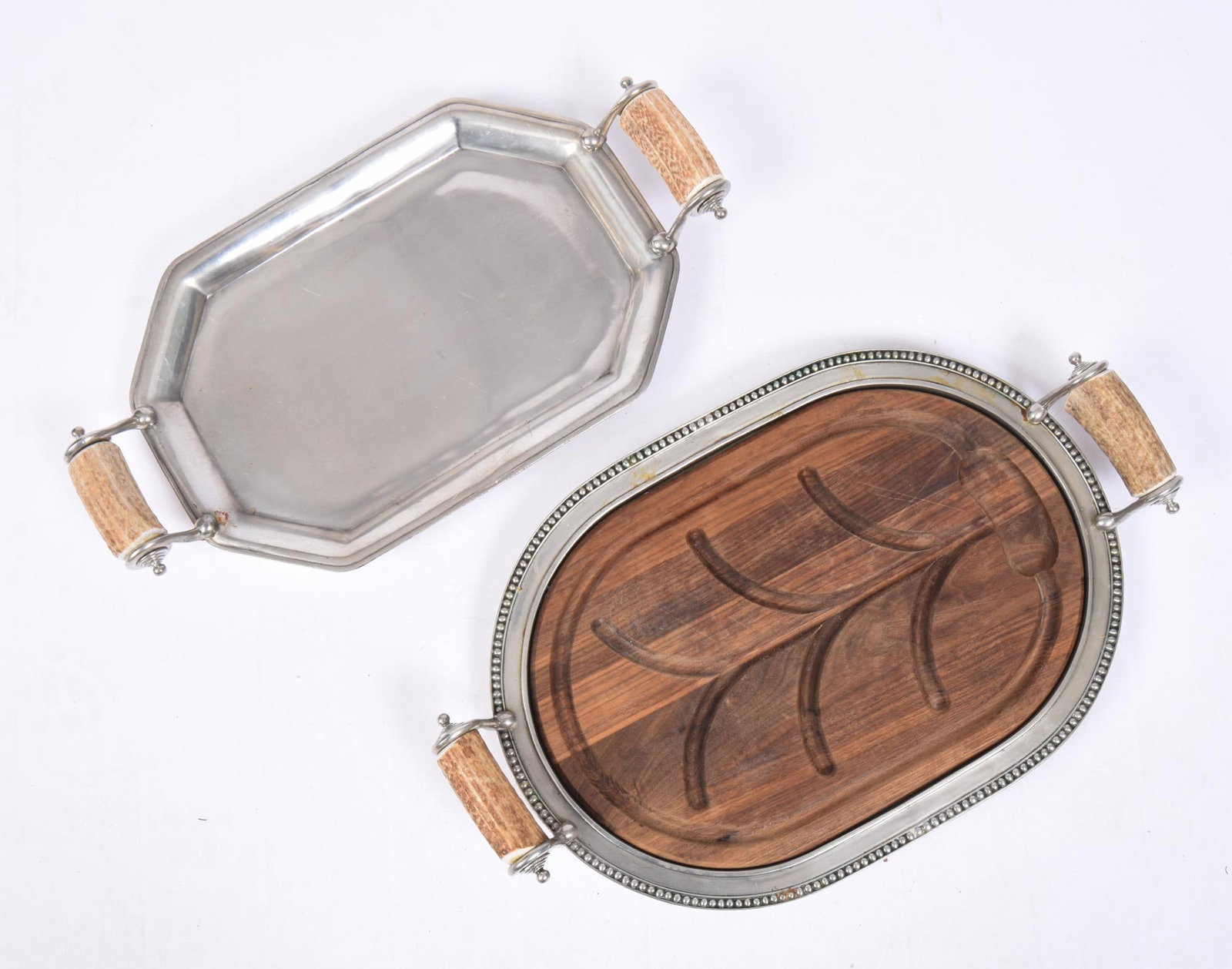 TWO PEWTER PLATTERS WITH BONE HANDLES: On ball and claw feet, one with wood well and tree insert, lengths 24 inches and 22 1/4 inches