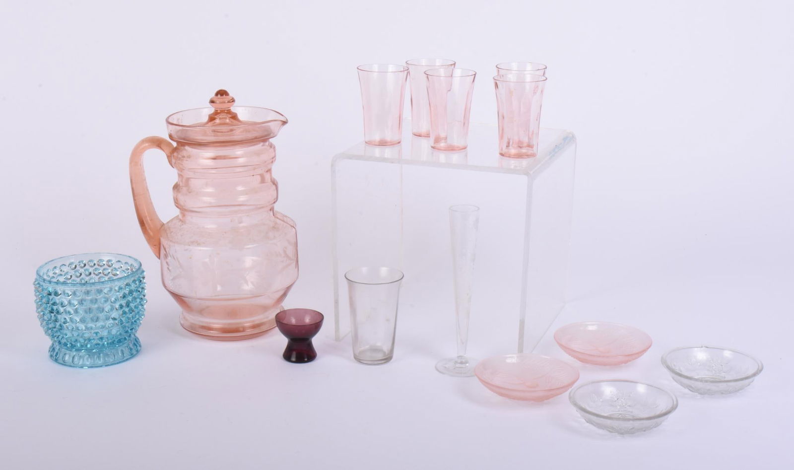 Collection of Glassware.: Pink pitcher with five glasses; one clear drinking glass; one bud vase with floral etching; one small purple egg cup; blue Fenton style bowl; four small dishes. Height of bud vase 6.5 inches.