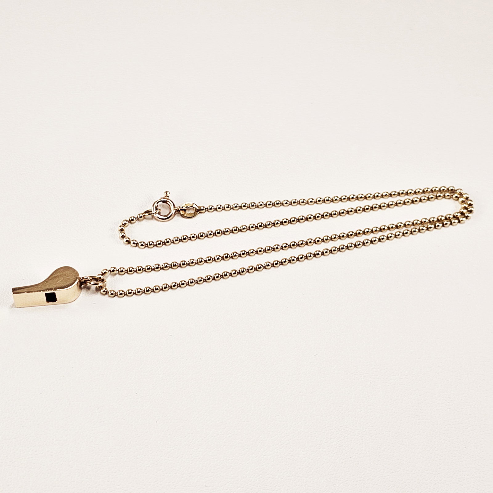 Tiffany & Co. 14k Yellow Gold Whistle Necklace: Featuring a Tiffany & Co. 14k yellow gold pendant designed as a whistle, measuring approximately 15.70 x 5.93 mm, suspended by a 14k yellow gold, 15 inch bead chain completed by a spring ring clasp. G