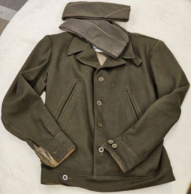 Lot of Military jacket and Two fabric hats: Military garments, includes 2 Folded Garrison style hats, one with metal, and 1 Jacket has pleated back, some discoloration (as shown on cuff example), buttons appear in good order.