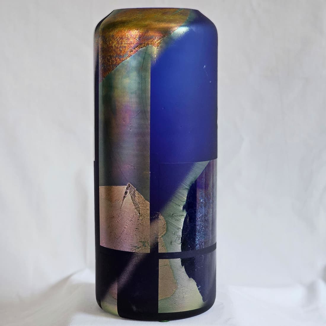 Blue Art Glass Vase by Steven Maslach: Cylindrical glass vase of bold blue with patches of metallic and other textural components. Signed on base Maslach '82. 10.75" H x 4.25" D