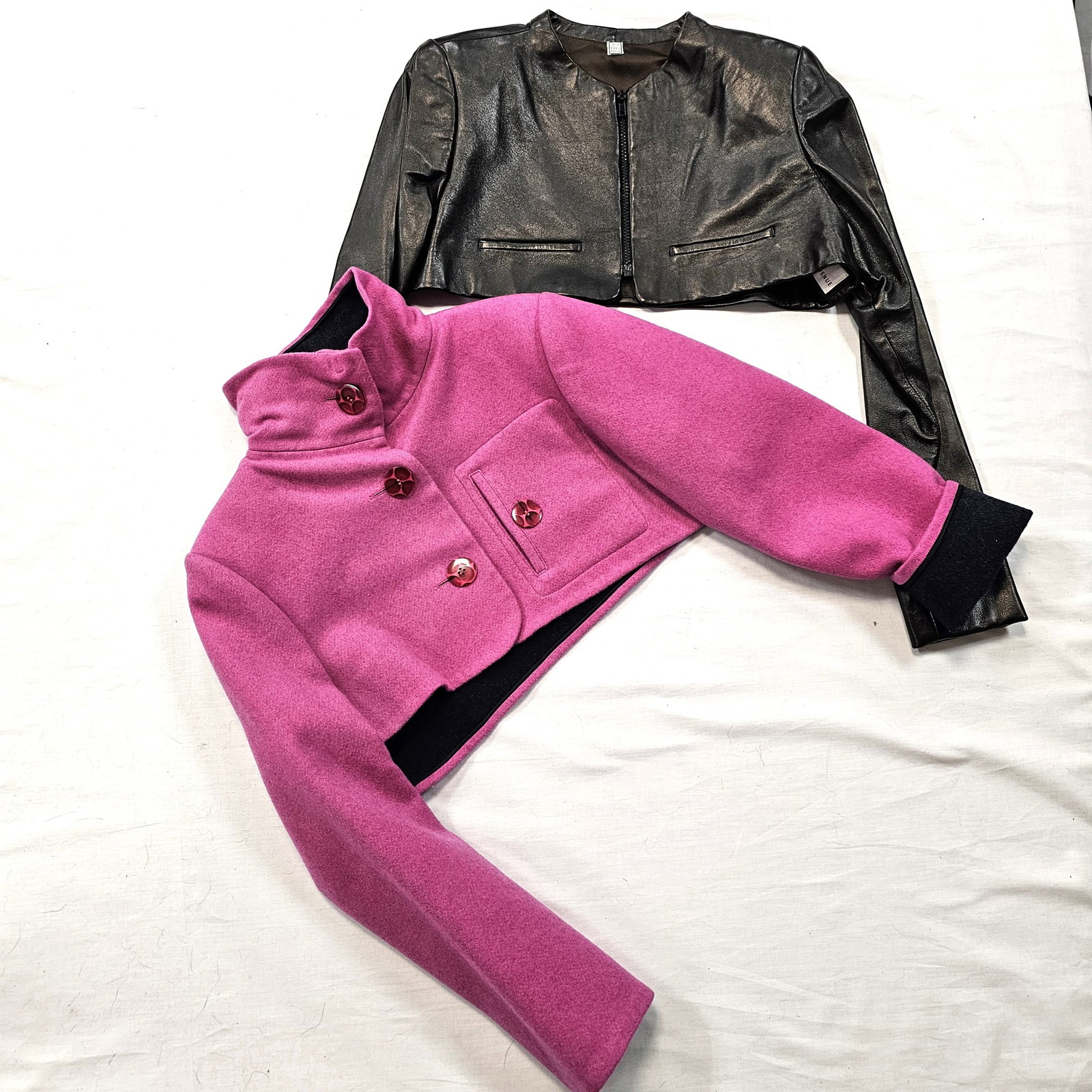 Group of Two Geoffrey Beene Boleros: Group of two vintage Geoffrey Beene boleros, one collared pink and gray felted wool with button front, one black leather with zipper front.