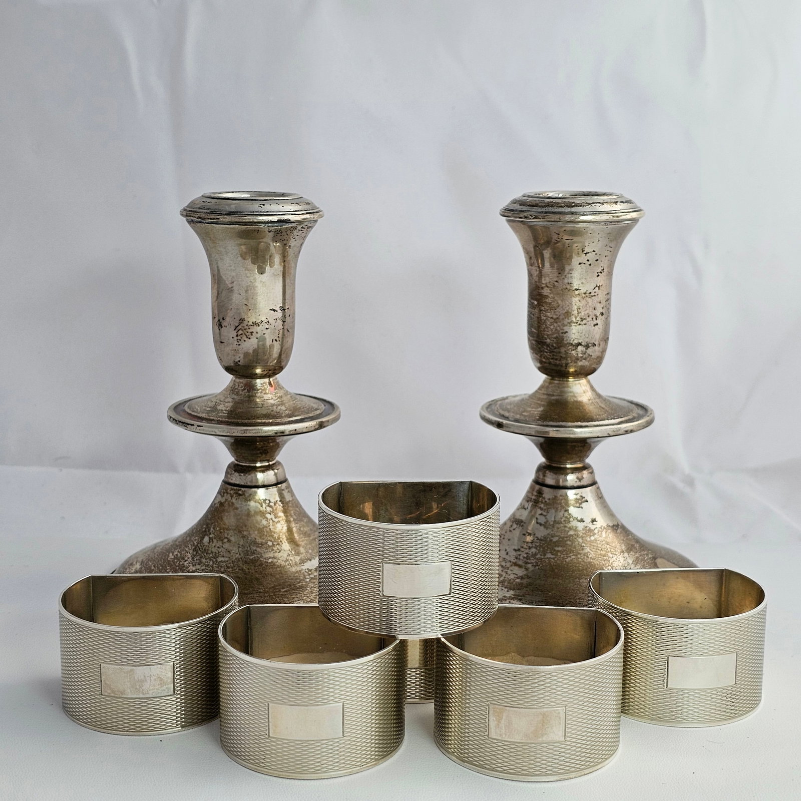 Grouping of Sterling Silver Napkin Rings and Candleholders: Grouping of sterling silver napkin rings and pair of weighted Reed & Barton candlesticks. Total gross weight for the napkin rings is approximately 212.9. 