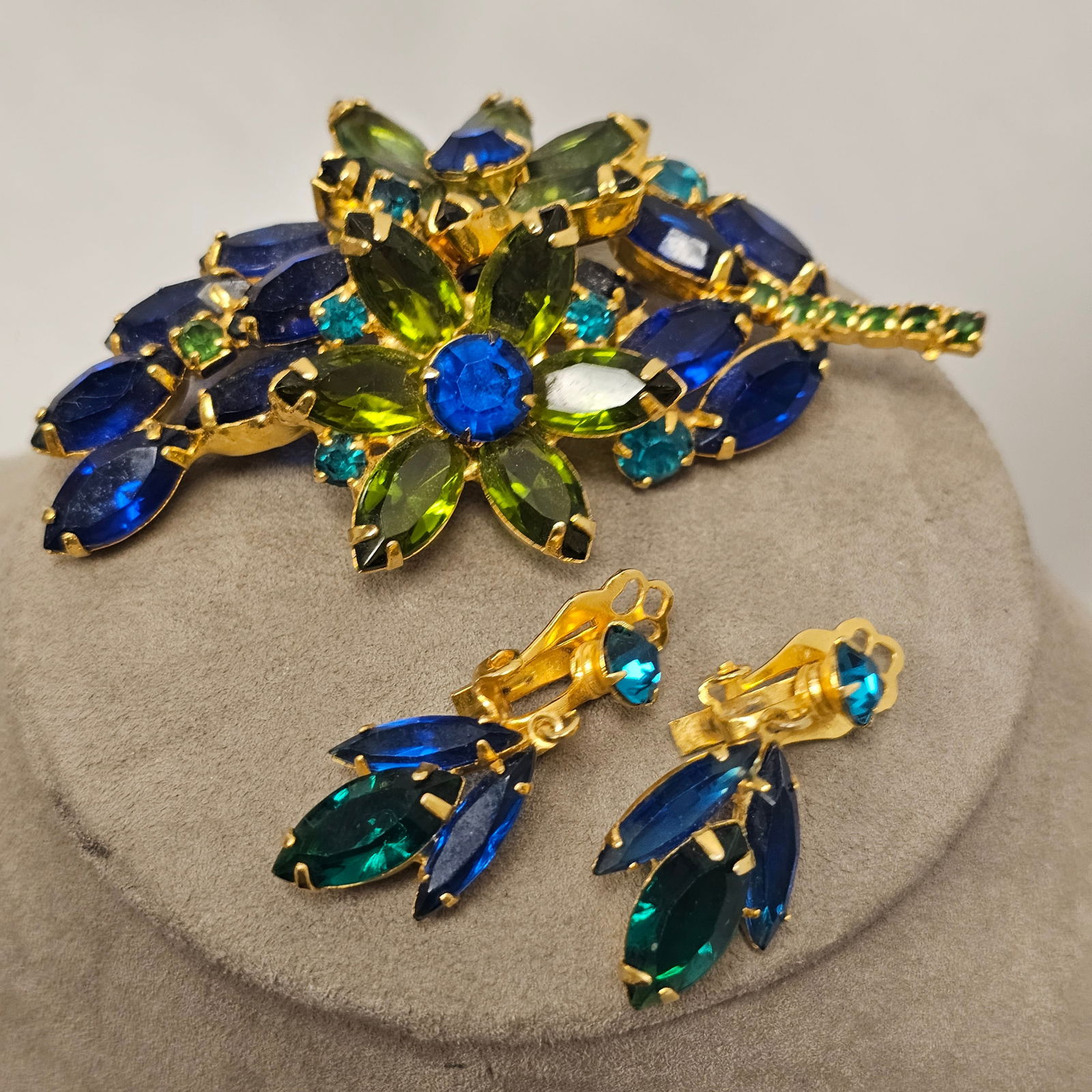 Vintage Brooch and Ear Clip Set: Vintage floral spray brooch with blue and green stones together with matching ear clips. Brooch measures approximately 3 1/2 in L x 2 in W. Earrings measure approximately 1 1/2 L. Condition is very go