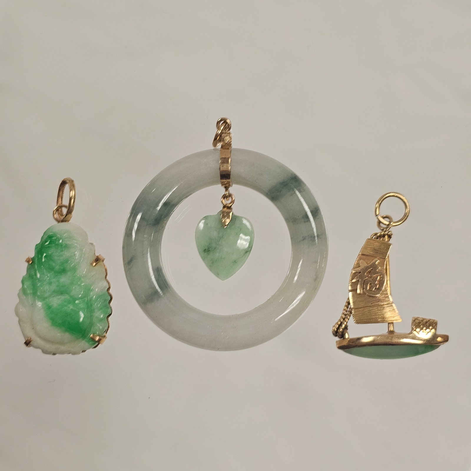 Collection of Jade, 18k, 14k Yellow Gold Pendants: Including a pendant designed as a Chinese junk, the sail and rigging 14k yellow gold, the hull a marquise-shape jade cabochon, measuring approximately 24.0 x 18.0 mm (0.95 x 0.70 in); a pendant compos