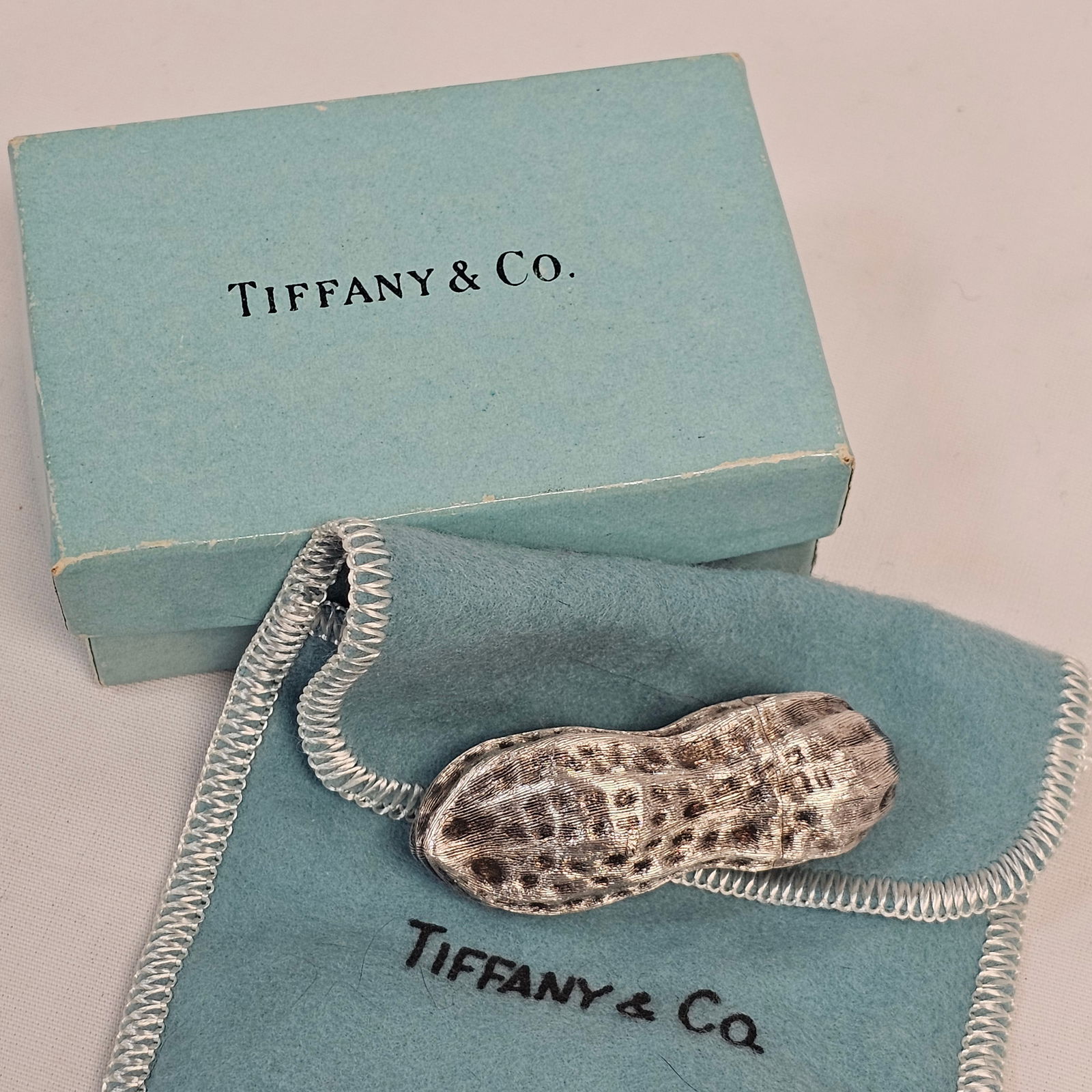 Tiffany & Co Sterling Silver Peanut Pill Box: Tiffany & Co. sterling silver peanut shaped pill box with dust cover and box. Peanut weighs approximately 17.1 grams. Condition is good