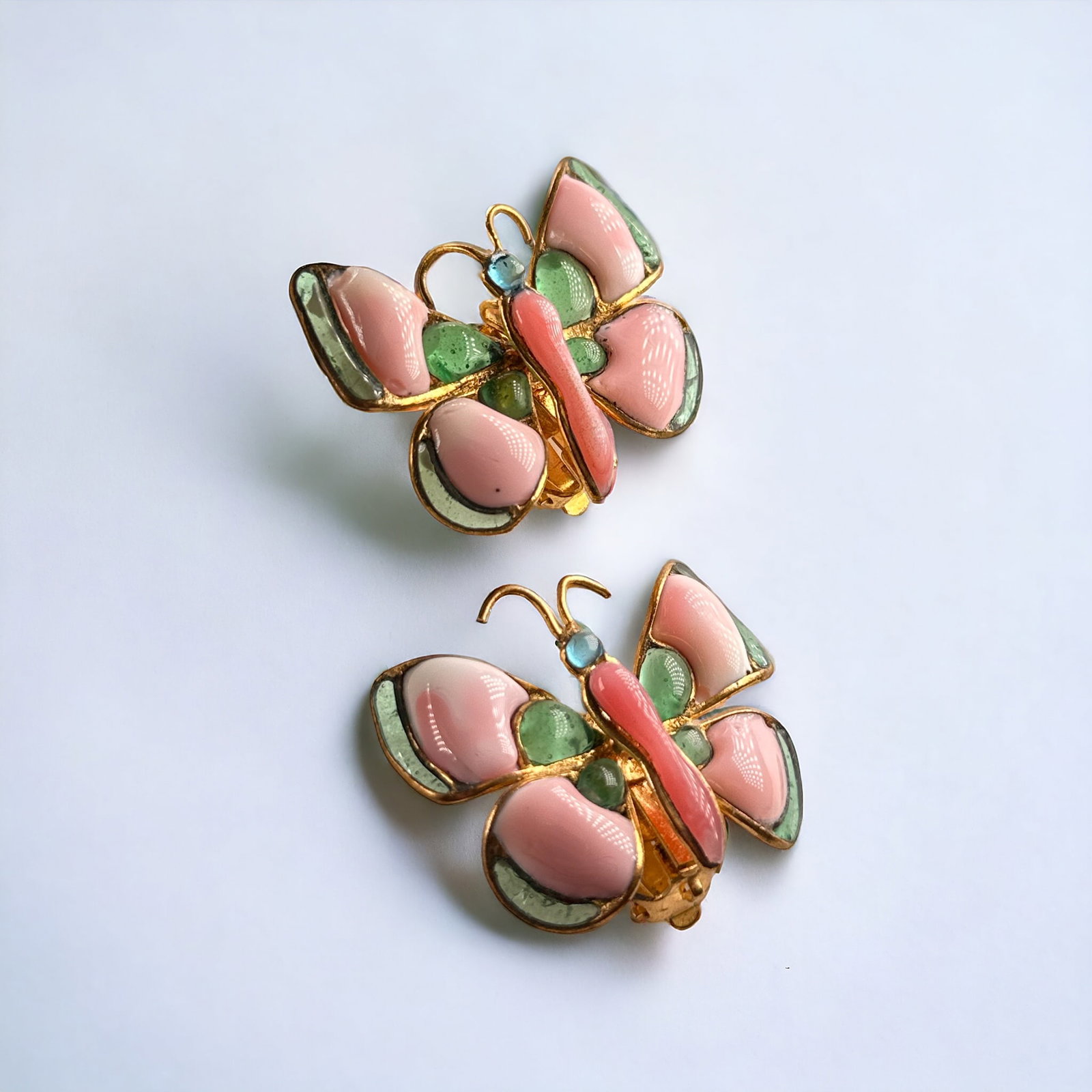 Pair of Gripoix Glass, Gilt Metal, Butterfly Ear Clips, Chanel: Designed as butterflies, the wings and body accented by pink, blue and green gripoix glass set in a gilt metal ear clip mounting, each measuring approximately 1.60 x 1.35 inches. Marked Chan