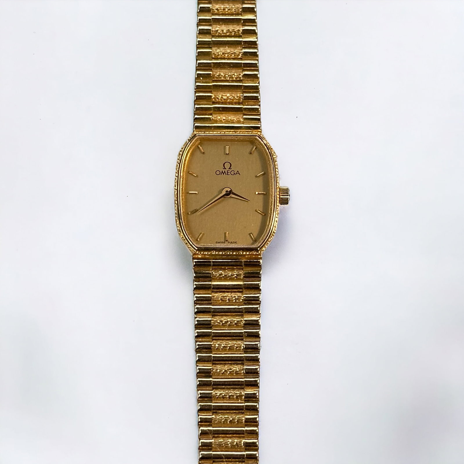 Ladies Omega, 14k Yellow Gold Wristwatch: DIAL: Barrel, champagne, applied gold index hour markers, gold dauphine hands, Omega, Swiss Made. MOVEMENT: Quartz. CASE: Barrel, 14k yellow gold, 20.0 x 16.0 mm. BRACELET: 14k yellow gold fitted wove