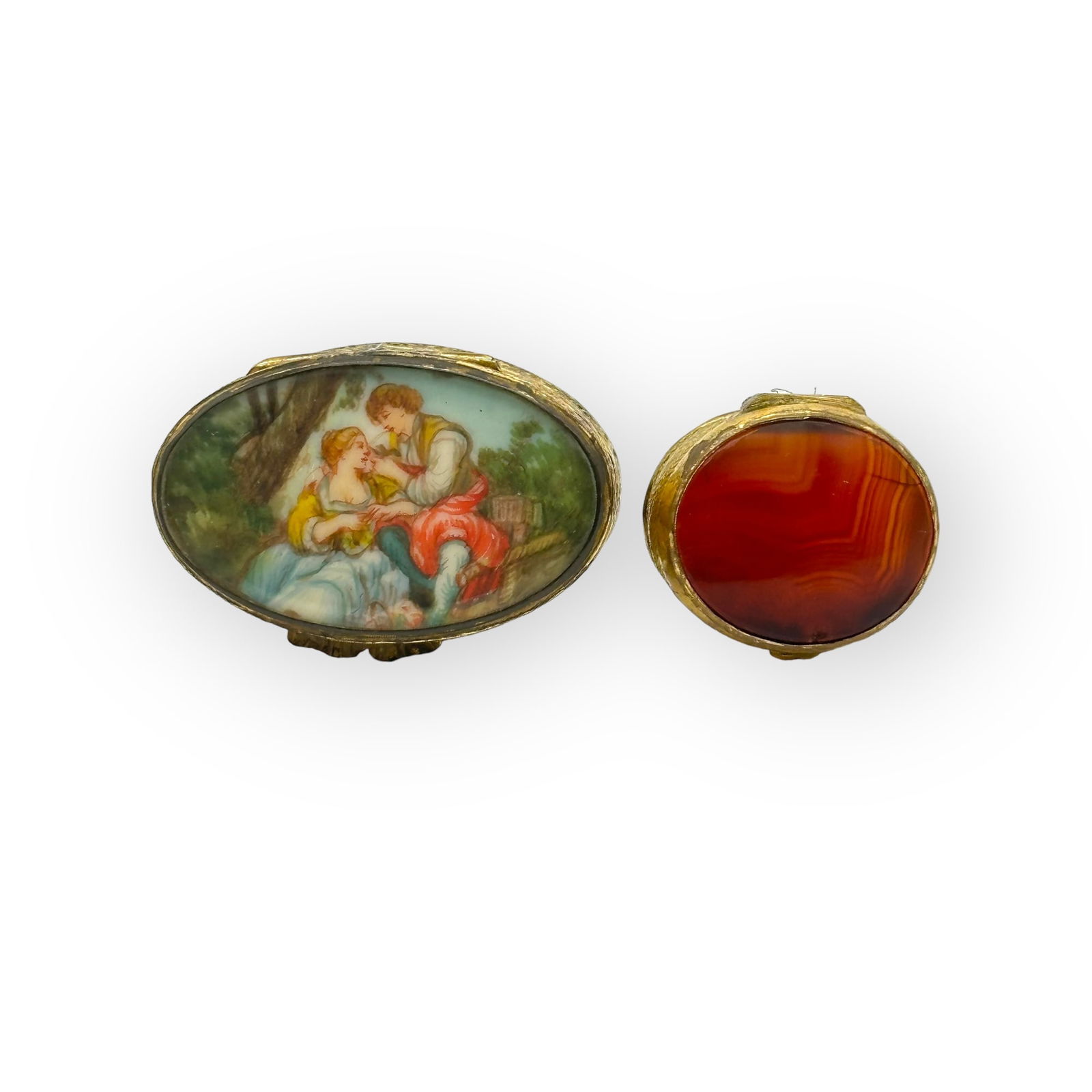 Collection of Two Antique Agate, Enamel, Gilt Pill Boxes: Including a hand painted miniature of lovers in a bucolic scene, topping an oval, silver gilt pill box measuring approximately 1.60 x 1.03 x 0.65 inches; together with two oval banded