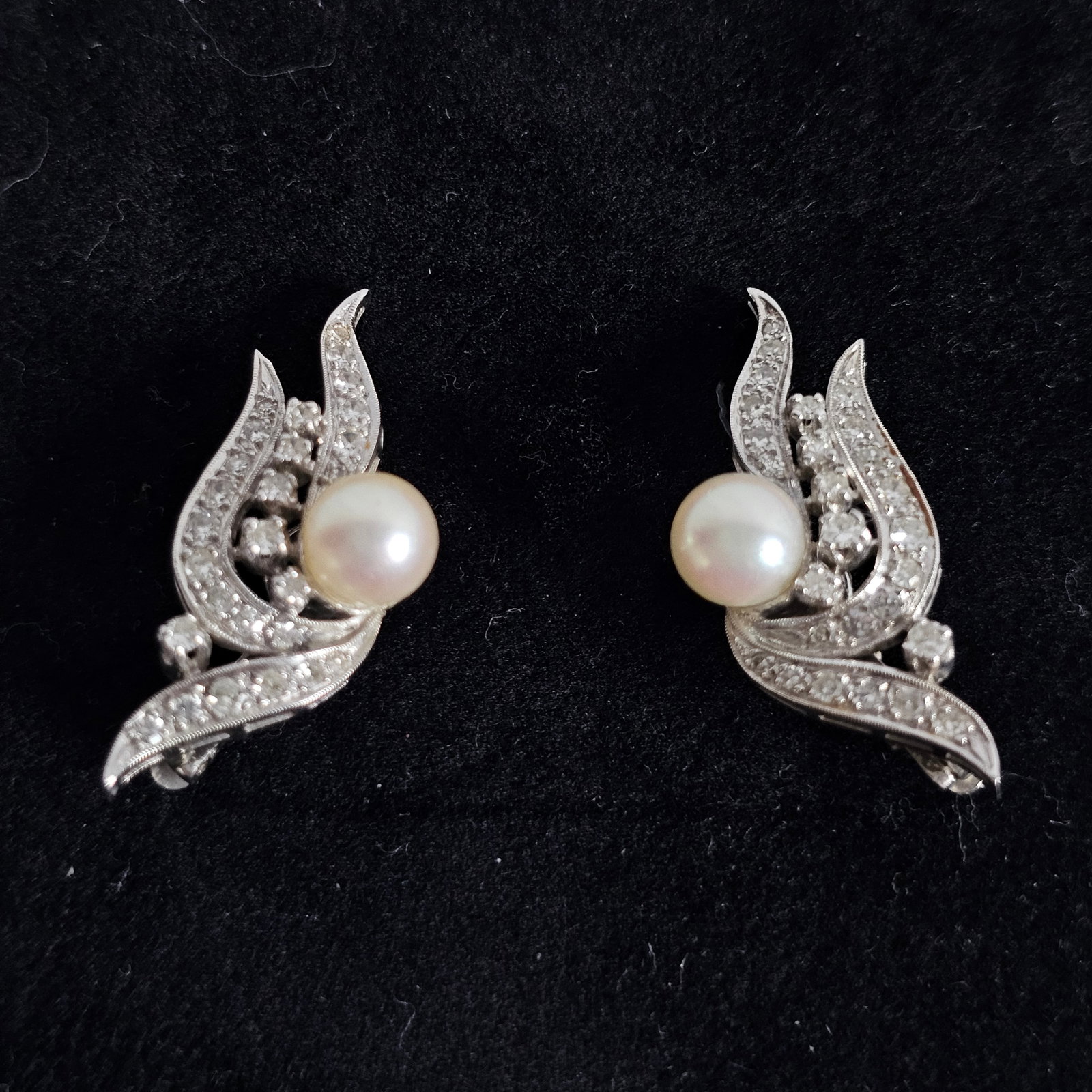 Pair of Diamond, Cultured Pearl, 14k White Gold Ear Clips: Each featuring one round cultured pearl measuring approximately 7.0 mm, accented by twenty-six single-cut diamonds weighing approximately 0.60 cttw., set in a 14k white gold ear clip mounting. T