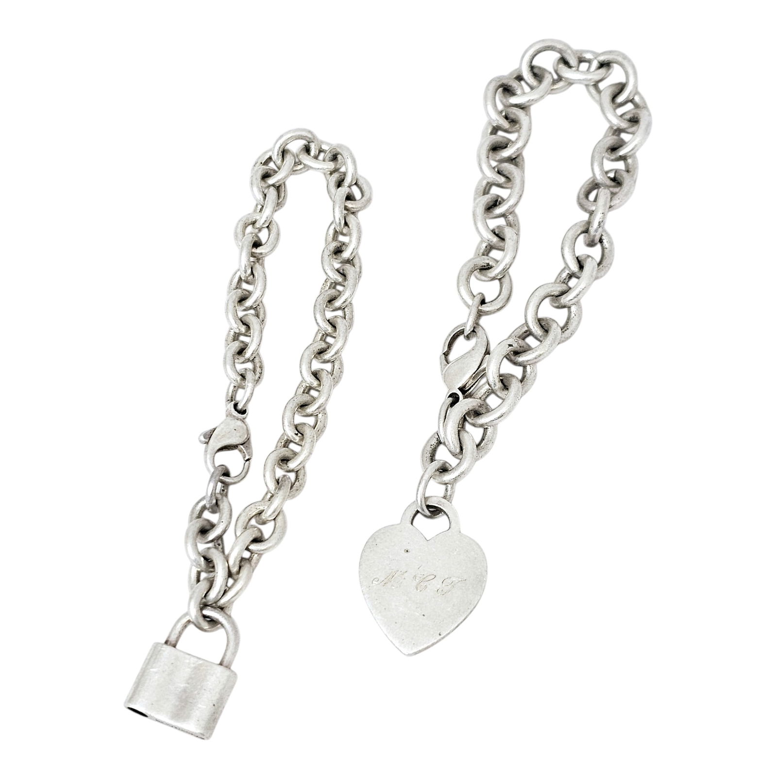 Two Sterling Silver Bracelets, Tiffany & Co.: Two sterling silver cable link bracelets, one featuring a heart-shaped plaque engraved "MCJ," reversing to "GEJ;" together with one featuring a padlock stating: "925, T &