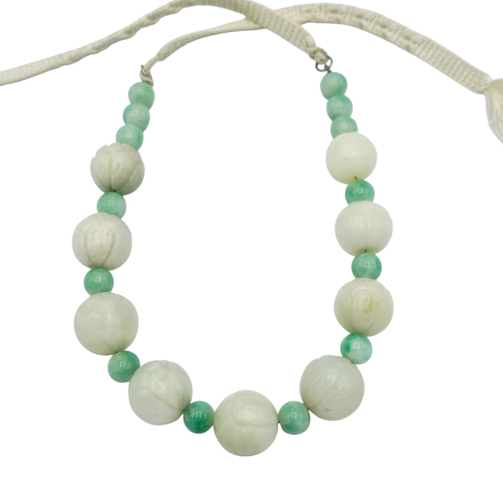 Carved Jade, Glass Necklace: Featuring nine carved jade beads, each measuring approximately 19.0 mm, spaced by fourteen green glass beads, each measuring approximately 9.5 mm, finished with woven ties, forming a 23 inch necklace.