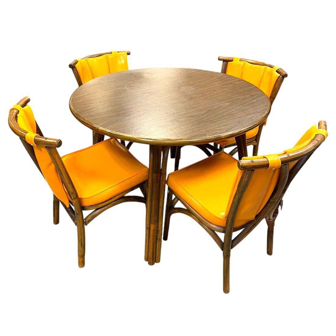 (Lot of 5) Circa 1975 McGuire Style rattan table and four chairs: the four chairs with orange vinyl upholstery, table: 42"dia. Absence of a condition report does not indicate that this lot is in perfect condition. Please request a condition report as needed, pr