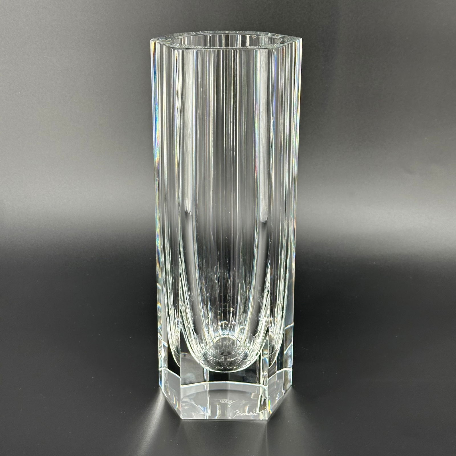 Baccarat French Crystal Cylinder Vase: Signed Baccarat cylinder vase cut in 8 faceted sides of varying sizes. Signed on the side and stamped on the bottom. Measures approximately 11 inches tall. Has a minor chip to one edge, otherwise in v