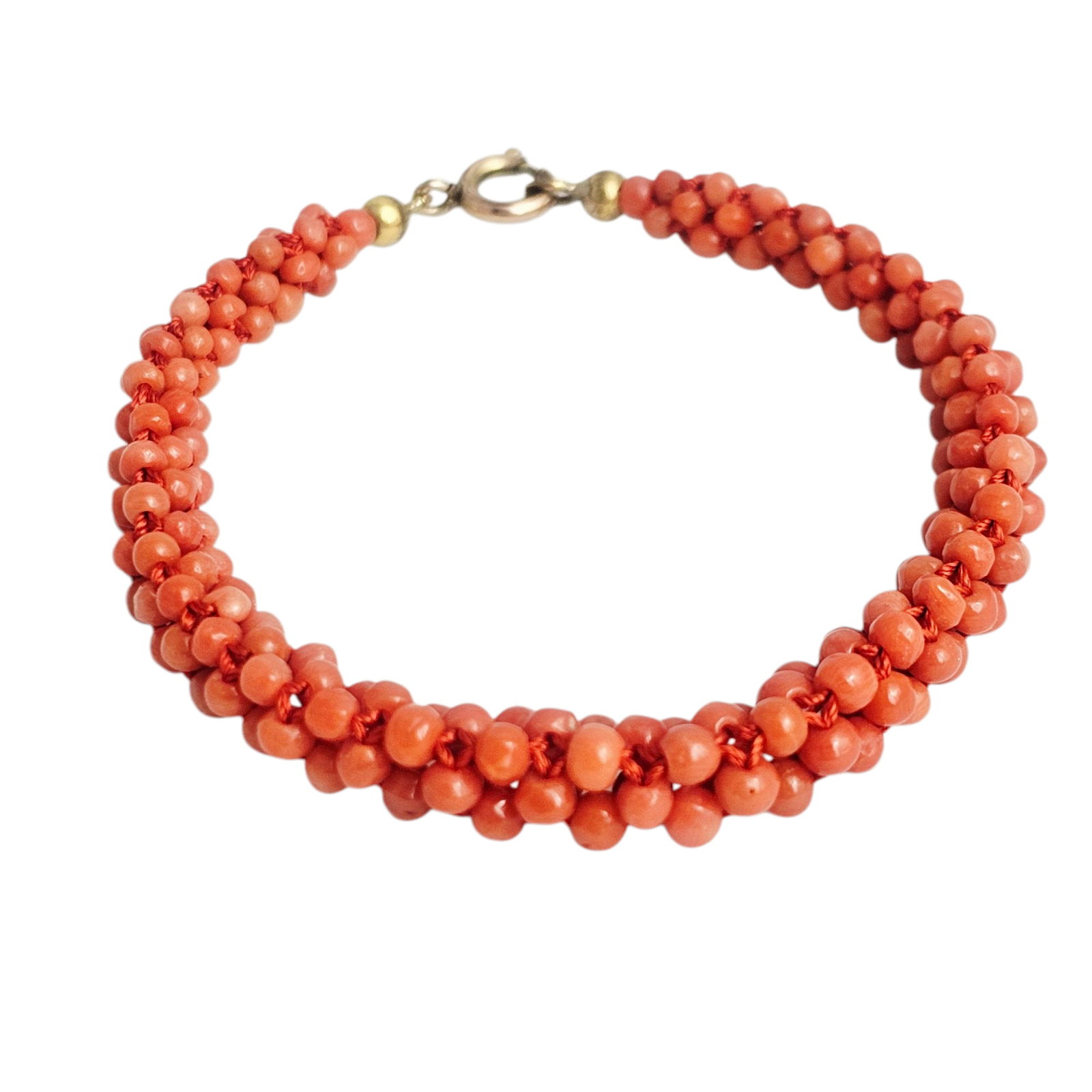 Vintage Coral Bracelet: Comprised of numerous woven coral beads, completed by a gold-tone spring ring clasp forming a 7 1/2 inch bracelet. Gross weight: 9.0 grams. Absence of a condition report does not indicate th