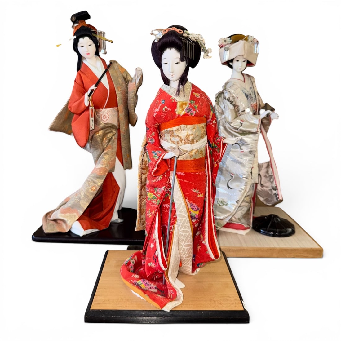 (Lot of) 3 Classical Japanese Dolls: (Lot of) 3 classical Japanese Oyama, Geisha, and Shinto bride dolls, each wearing a striking kimono with traditional hair ornaments, standing on a plinth.