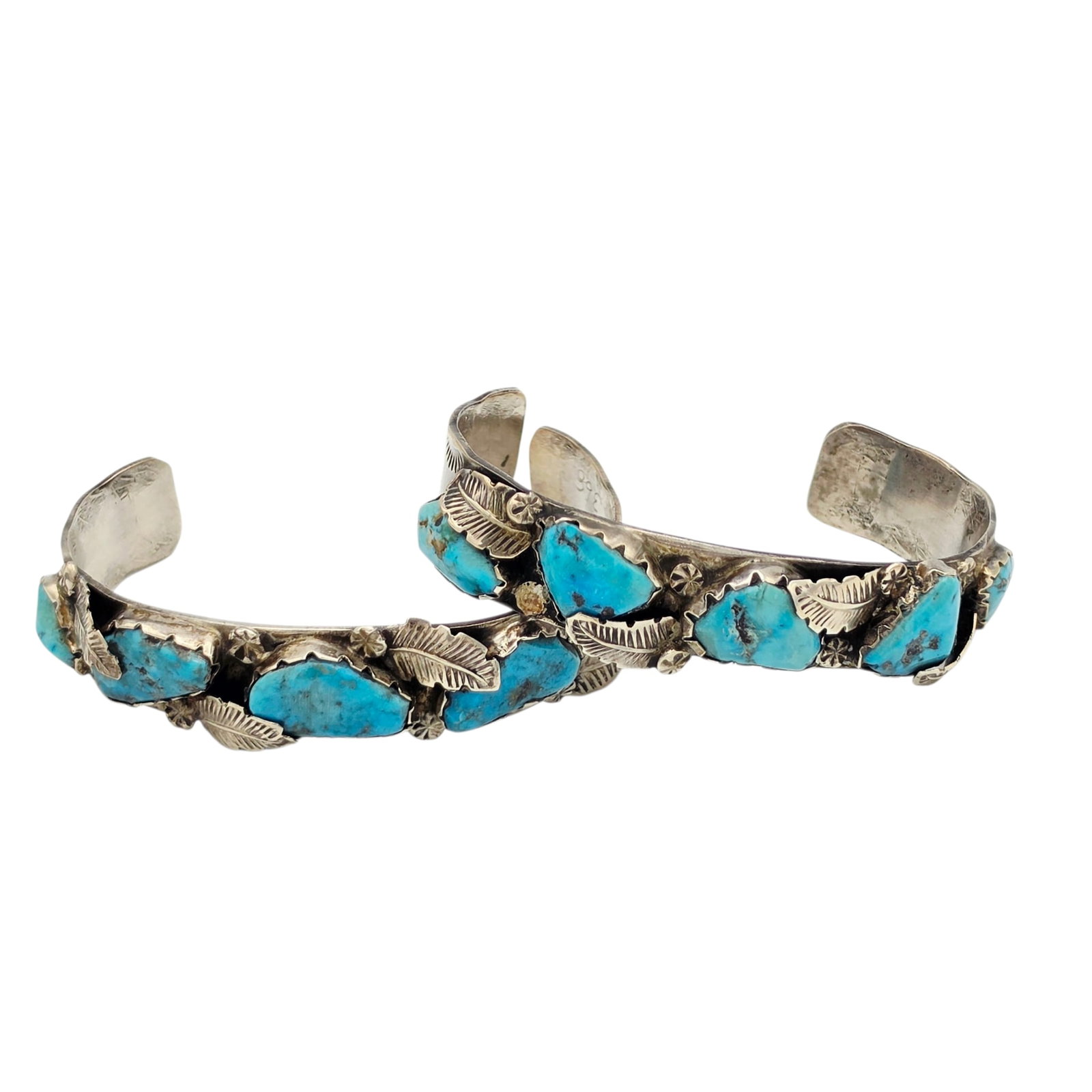 Pair of Zuni Turquoise, Sterling Silver Cuff Bracelets: The matching pair, each featuring five tumbled turquoise set in a feather motif, sterling silver cuff bracelet mounting measuring approximately 0.55 inches (14.0 mm) in width, fitting to an inner circ