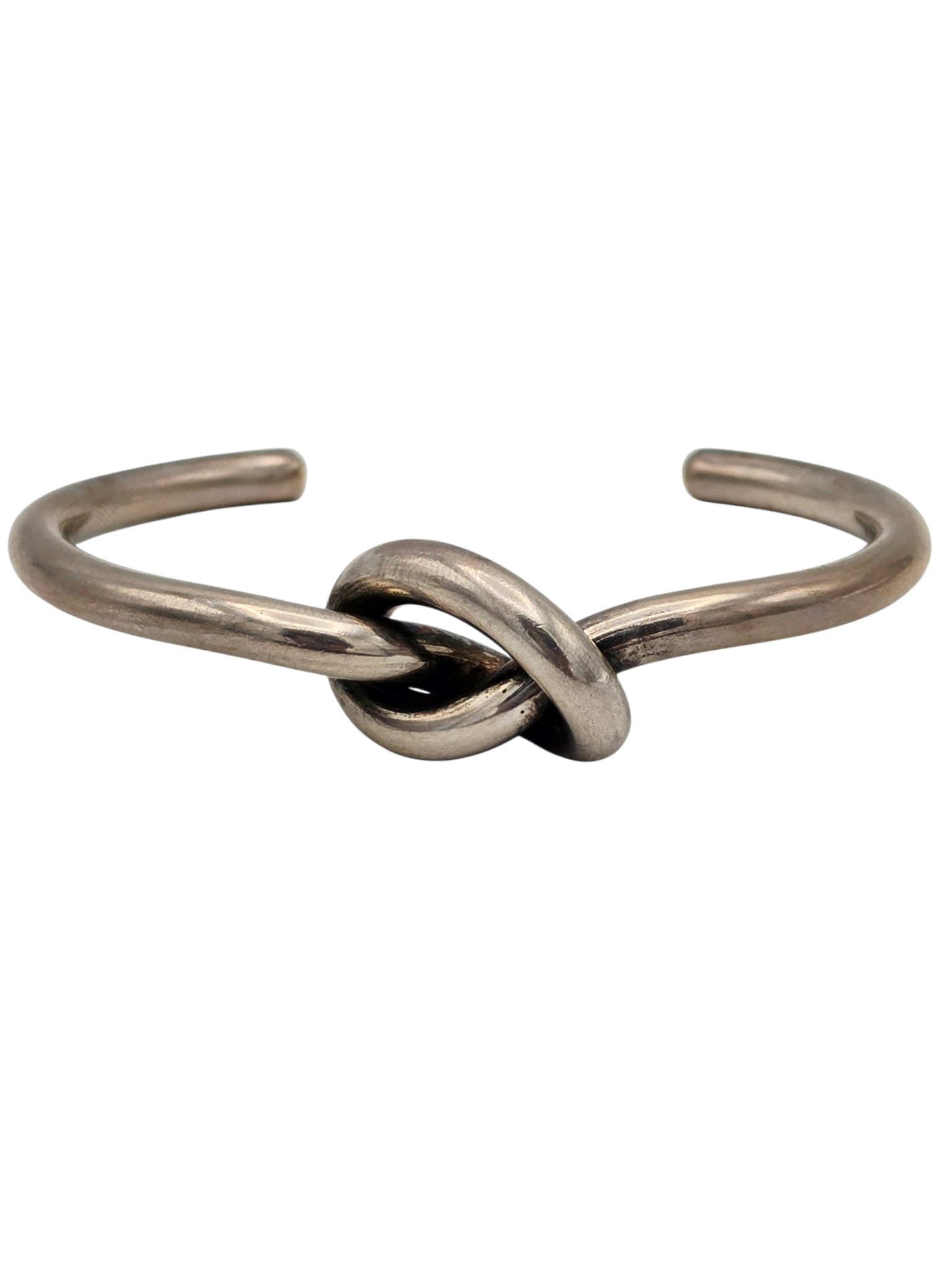 Georg Jensen Sterling Silver 'Love Knot' Bracelet: The sterling silver cuff centering a love knot, measuring approximately 0.70 (18.0 mm) at knot, 0.20 inches (5.0 mm), inner circumference 6 3/4, 1.30 inch gap. Marked: 'Georg Jensen within beaded 