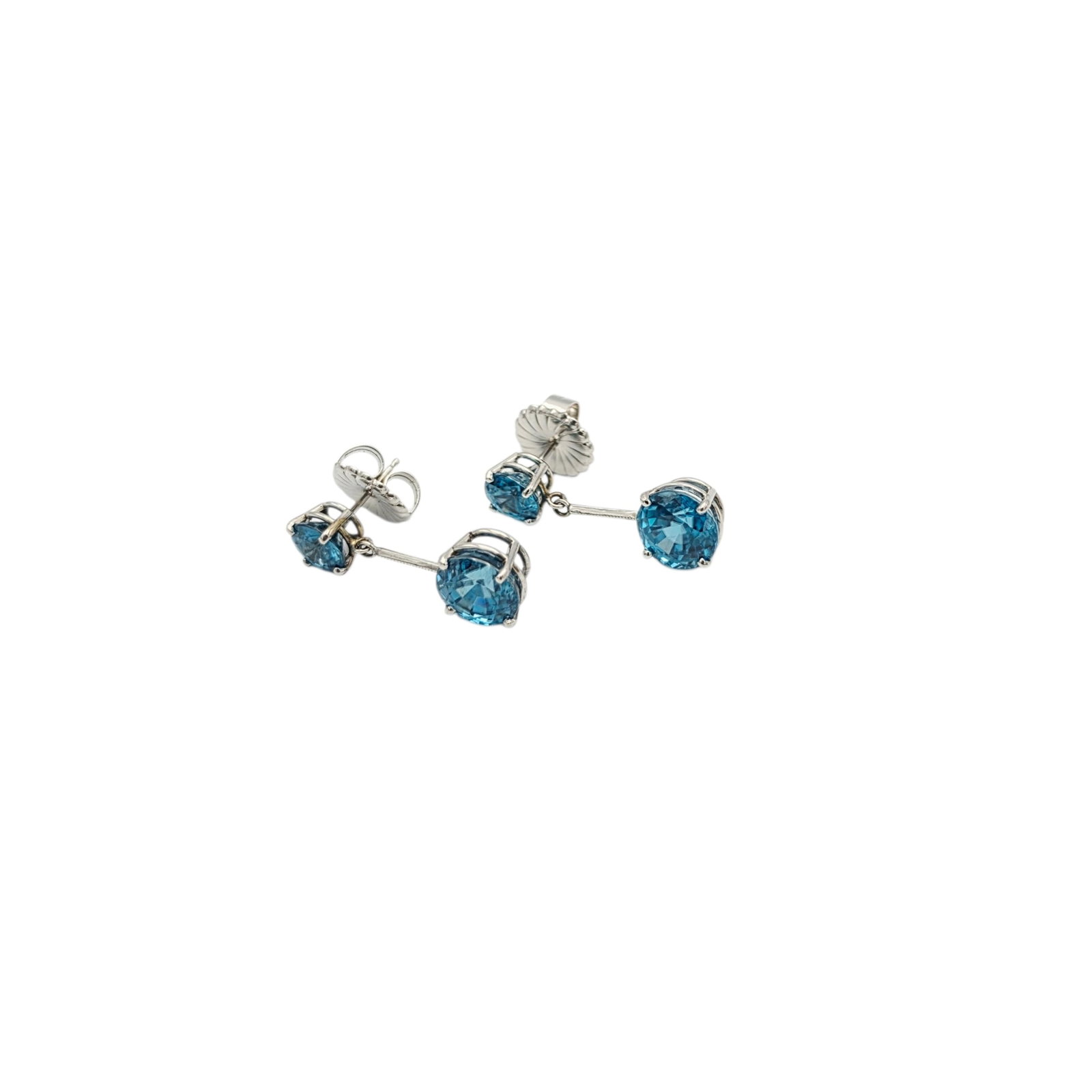 Pair of Zircon, 14k White Gold Earrings: Each featuring two round-cut blue zircons, set in articulated, 14k white gold earring mountings measuring approximately 1.00 inches in length. Total zircon carat weight for the pair approximately 11.5