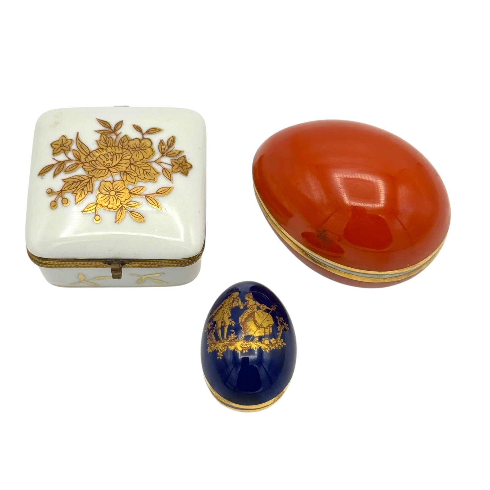 Lot of 3 French Porcelain Lidded Trinket & Egg Boxes including Limoges: A charming group of three (3) vintage French porcelain lidded trinket boxes, featuring two egg shaped boxes and one square hinged box, the eggs stamped with Limoges underneath.