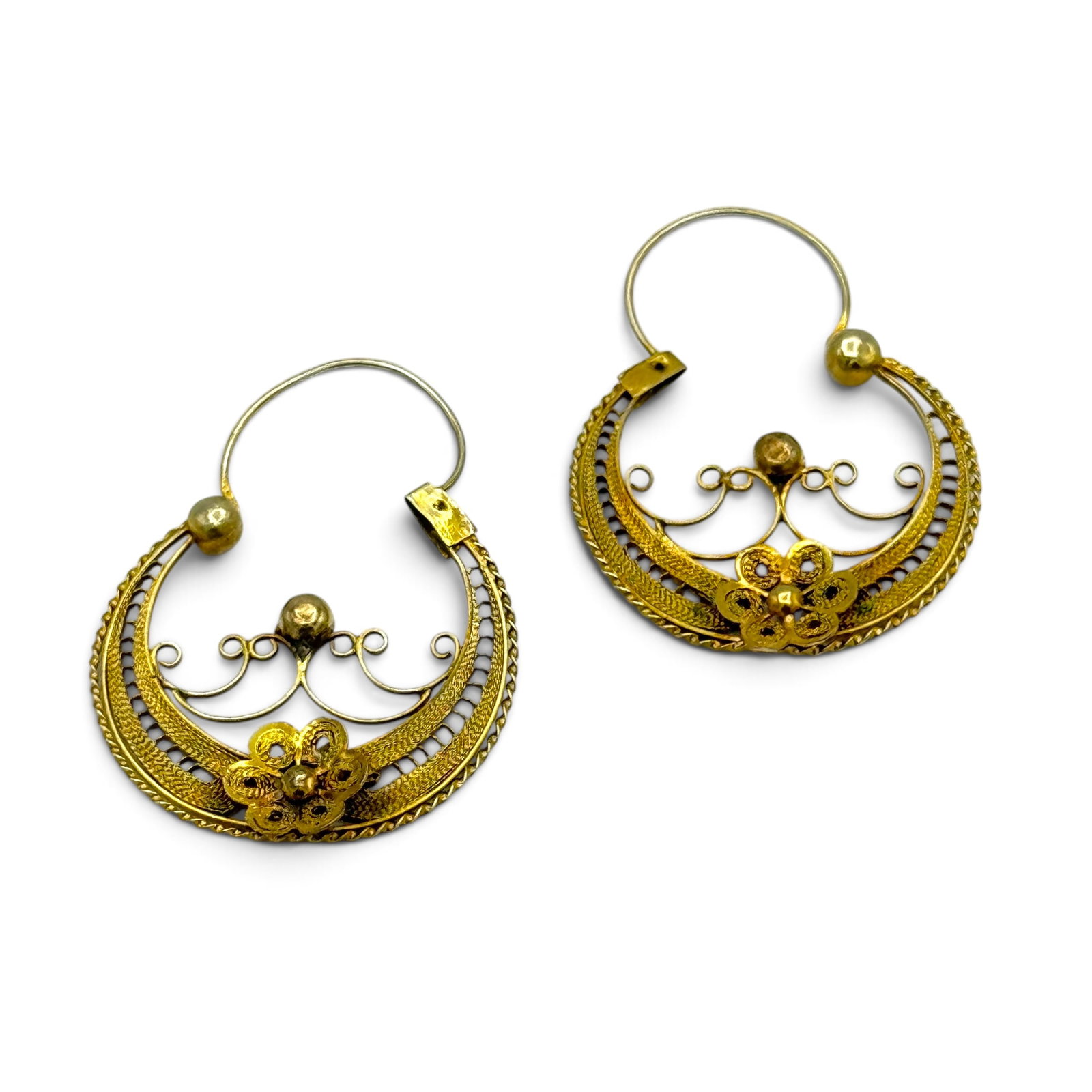 Pair of Antique Gold Filigree Earrings: Designed as a filigree half-hoop centering an applied flower, set in a tested-to 10k yellow gold earring mounting, each measuring approximately 14.5 x 1.05 inches. Gross weight: 3.5 grams.