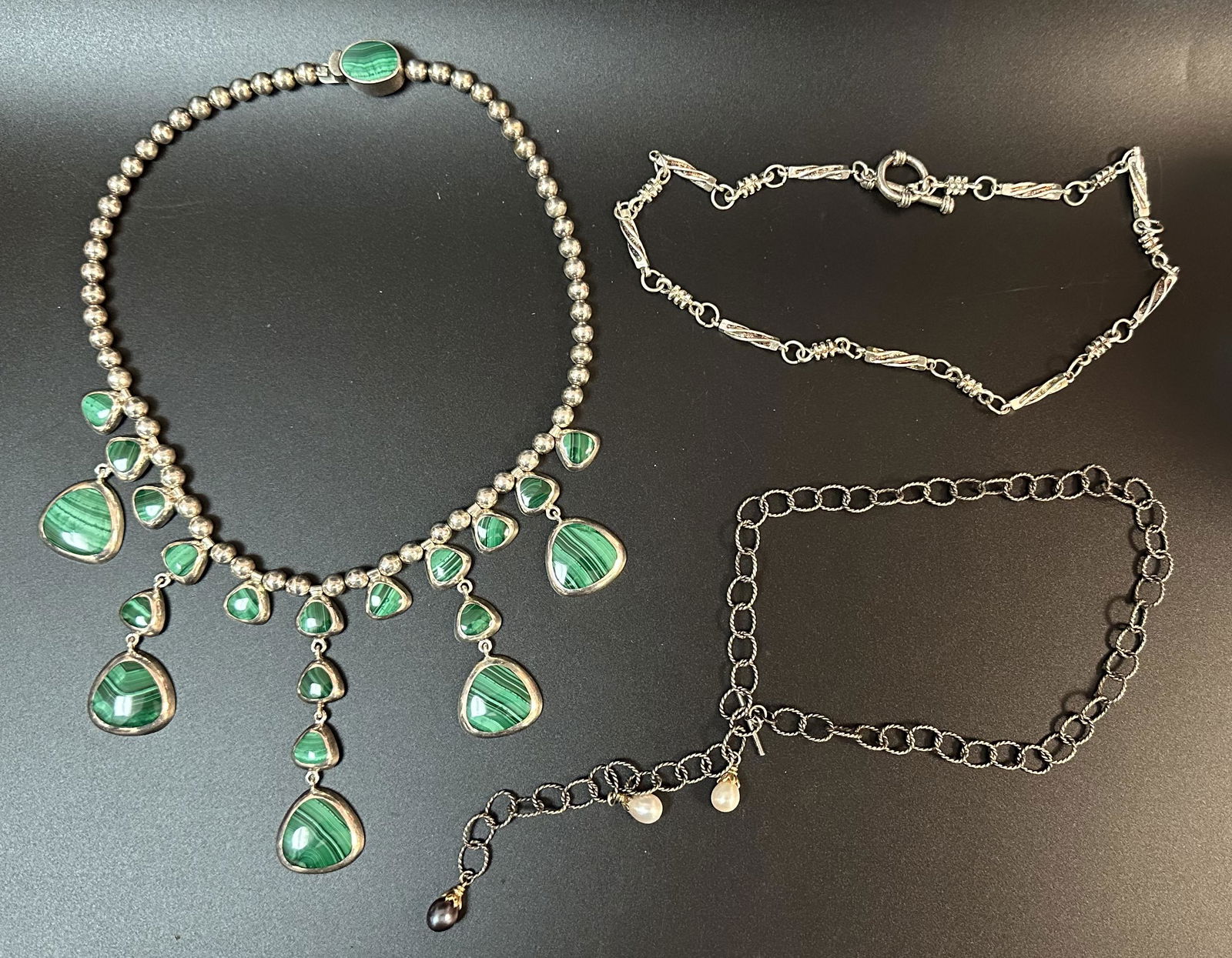 Silver and Stone Necklaces Lot B: This lot consists of a fantastic silver and malachite necklace, an 18 inch silver necklace with interesting bar/link design and a silver necklace with two white pearls and one black pearl.