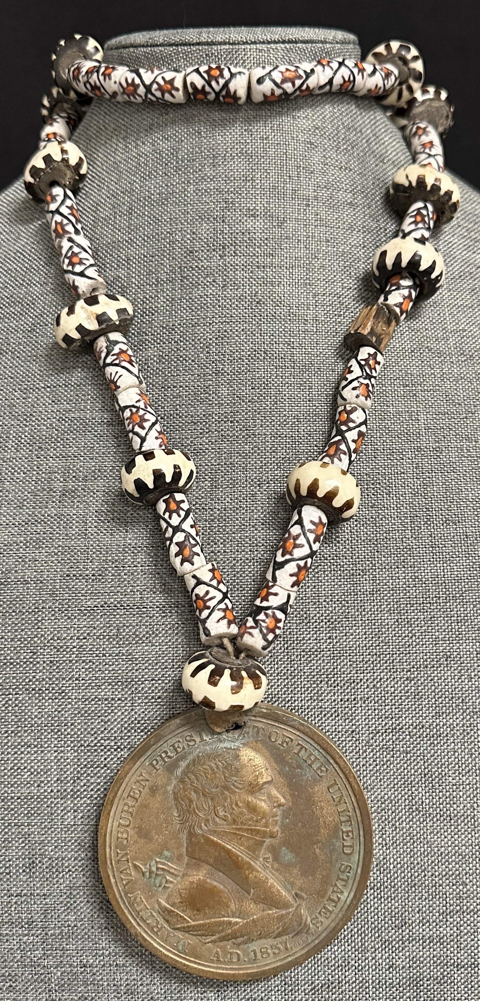 Martin Van Buren Peace Medal on Trade Bead Necklace: A Martian Van Buren bronze peace medal. The front has the bust of President Van Buren and the words, ?Martin Van Buren, President of the United States. AD 1837.? The back shows two hand shaking, a cro