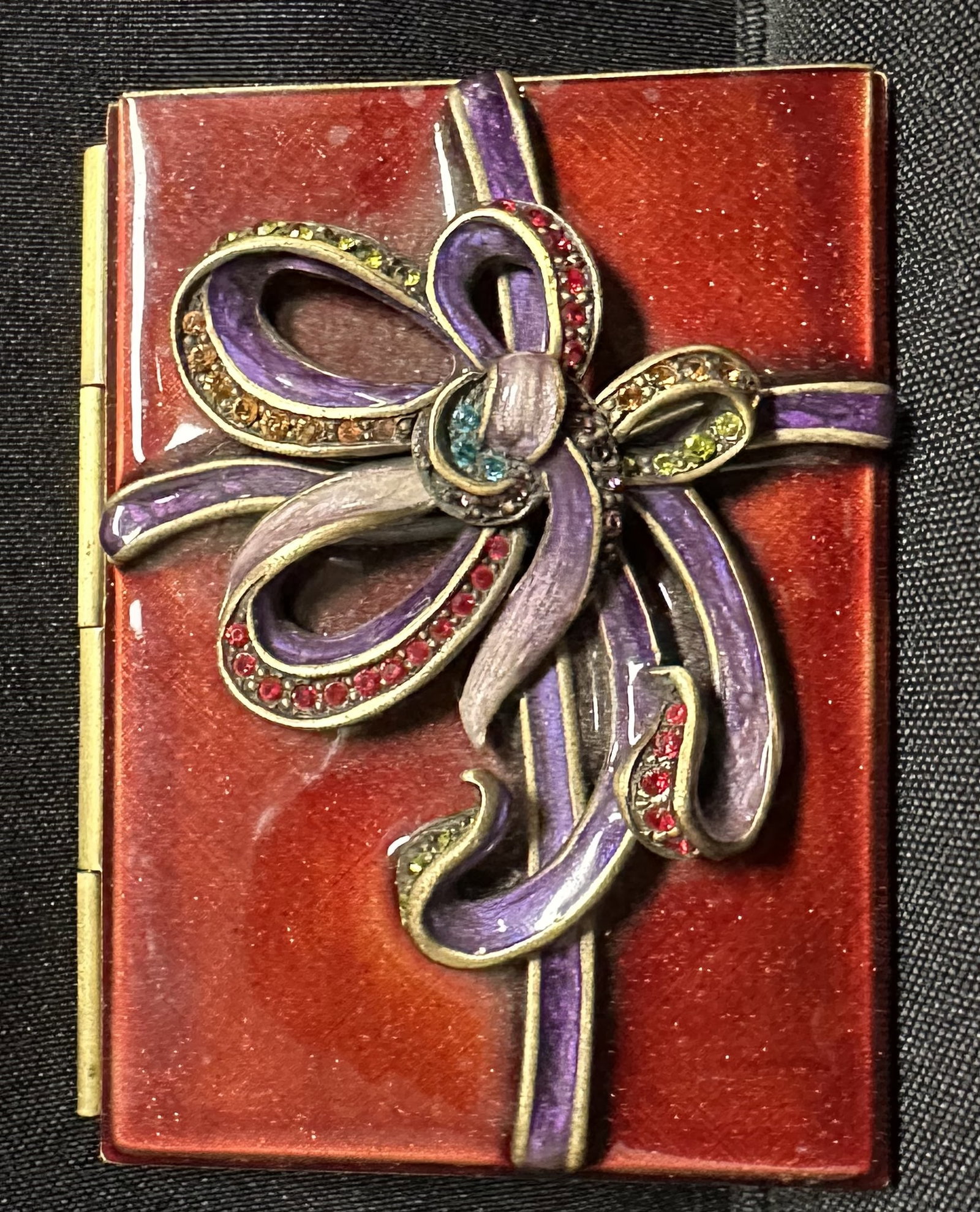 Jay Strongwater Enameled and Jeweled Travel Picture Frame: Jay Strongwater travel pocket frame with red and purple enamels and colorful stones lining the bows of a ribbon. Piece is in excellent shape as you can see. Great way to bring tokens of your loved one