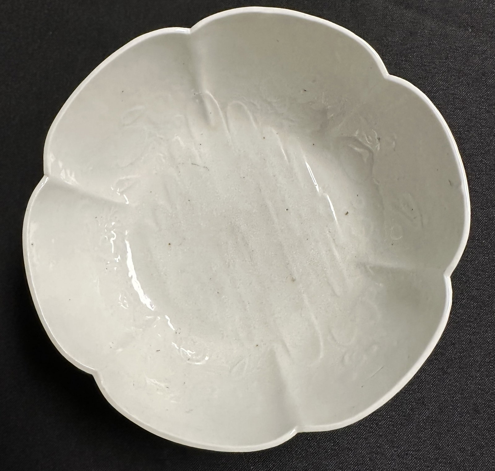 Antique Chinese White Glazed Bowl: Antique footed bowl in flower form with six lobes and what appears to be very old hand glazing. Measures about 6 1/2 inches across by 2 1/2 inches high.